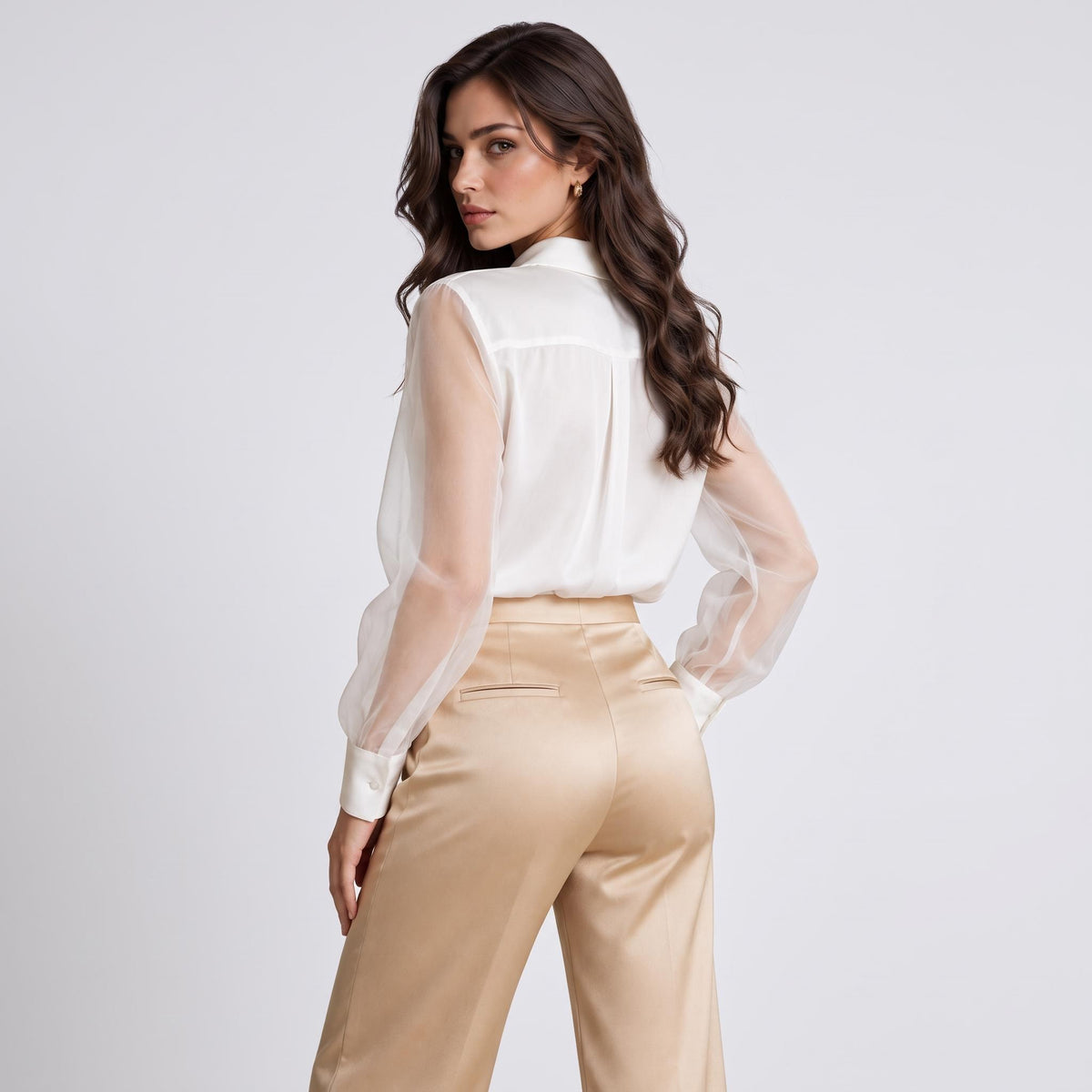 Elegant white silk blouse with sheer long sleeves and a classic lapel collar, paired with gold satin trousers.