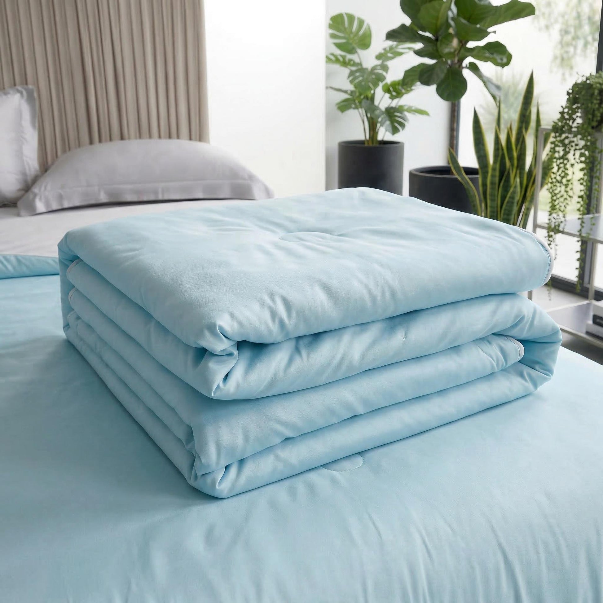 Light blue premium cooling blanket, neatly folded on a bed, with a reversible design.