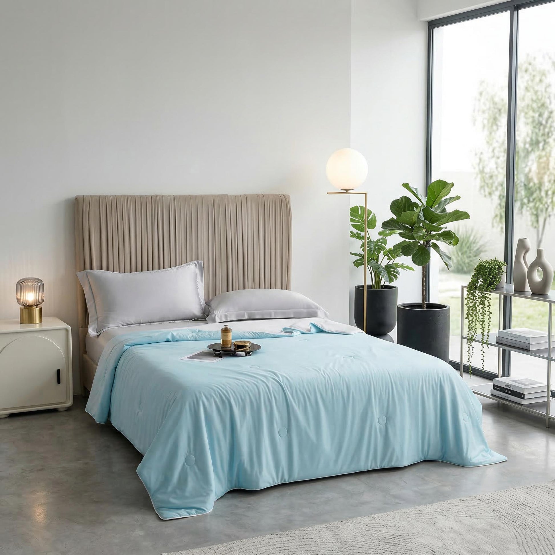 Light blue cooling blanket on a bed with a beige headboard in a modern bedroom.