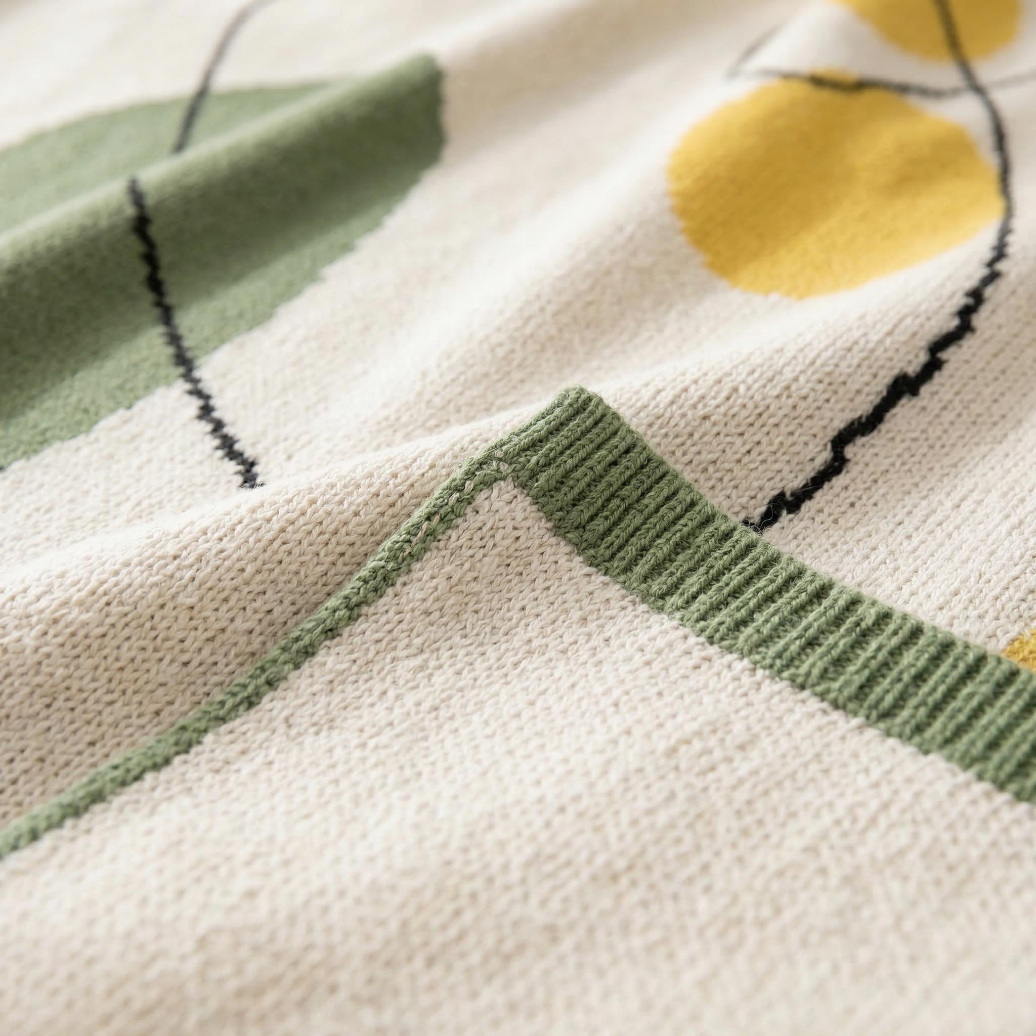 Abstract knitted throw blanket in earthy tones with organic shapes, featuring a soft, crocheted texture.