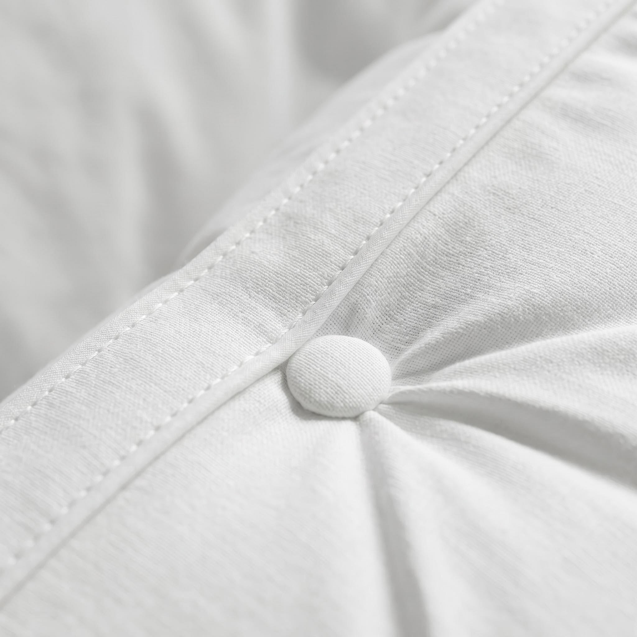 Close-up of a white quilted adjustable hotel pillow with a fabric-covered button detail.