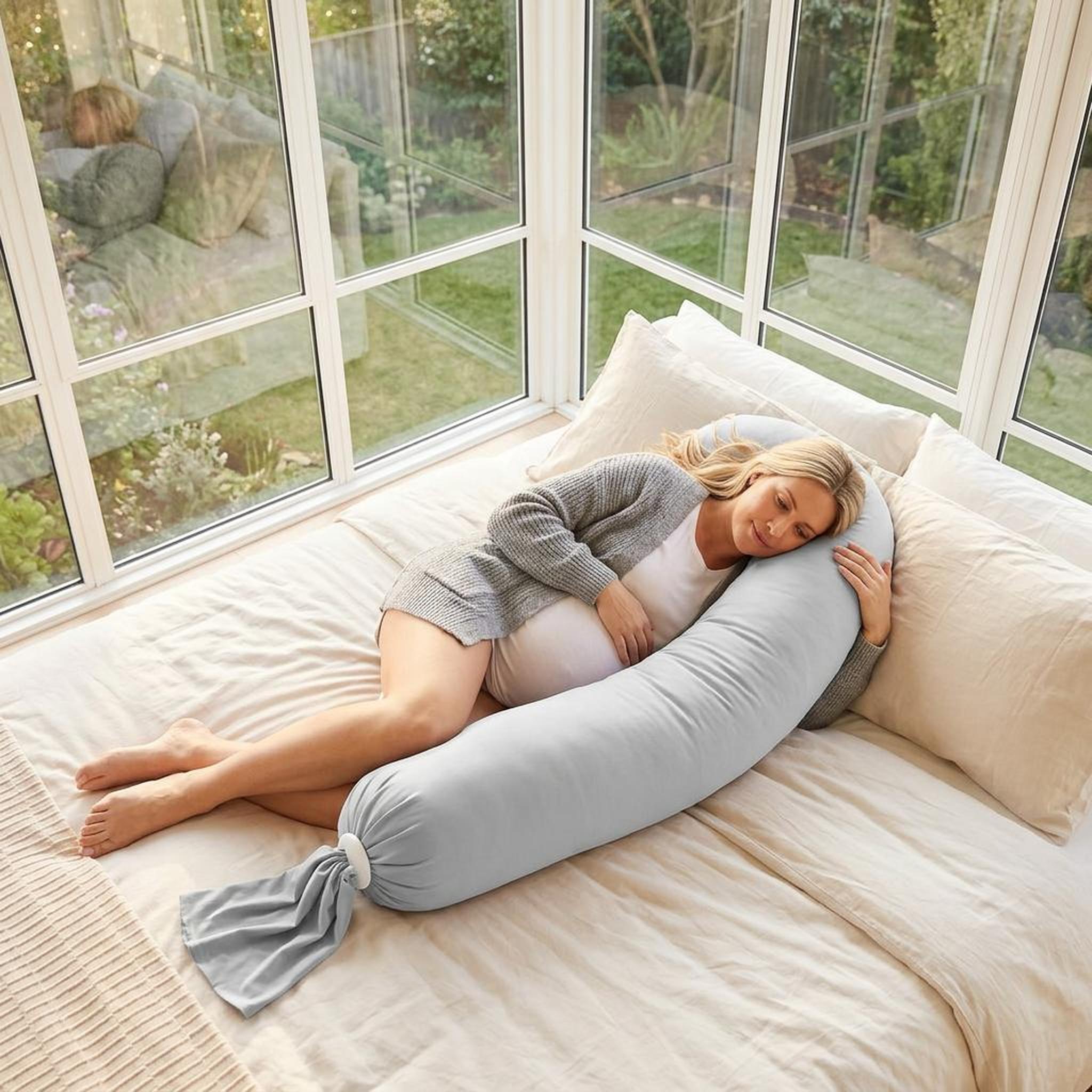 Pregnant woman sleeping comfortably on a light grey U-shaped body pillow with adjustable length.
