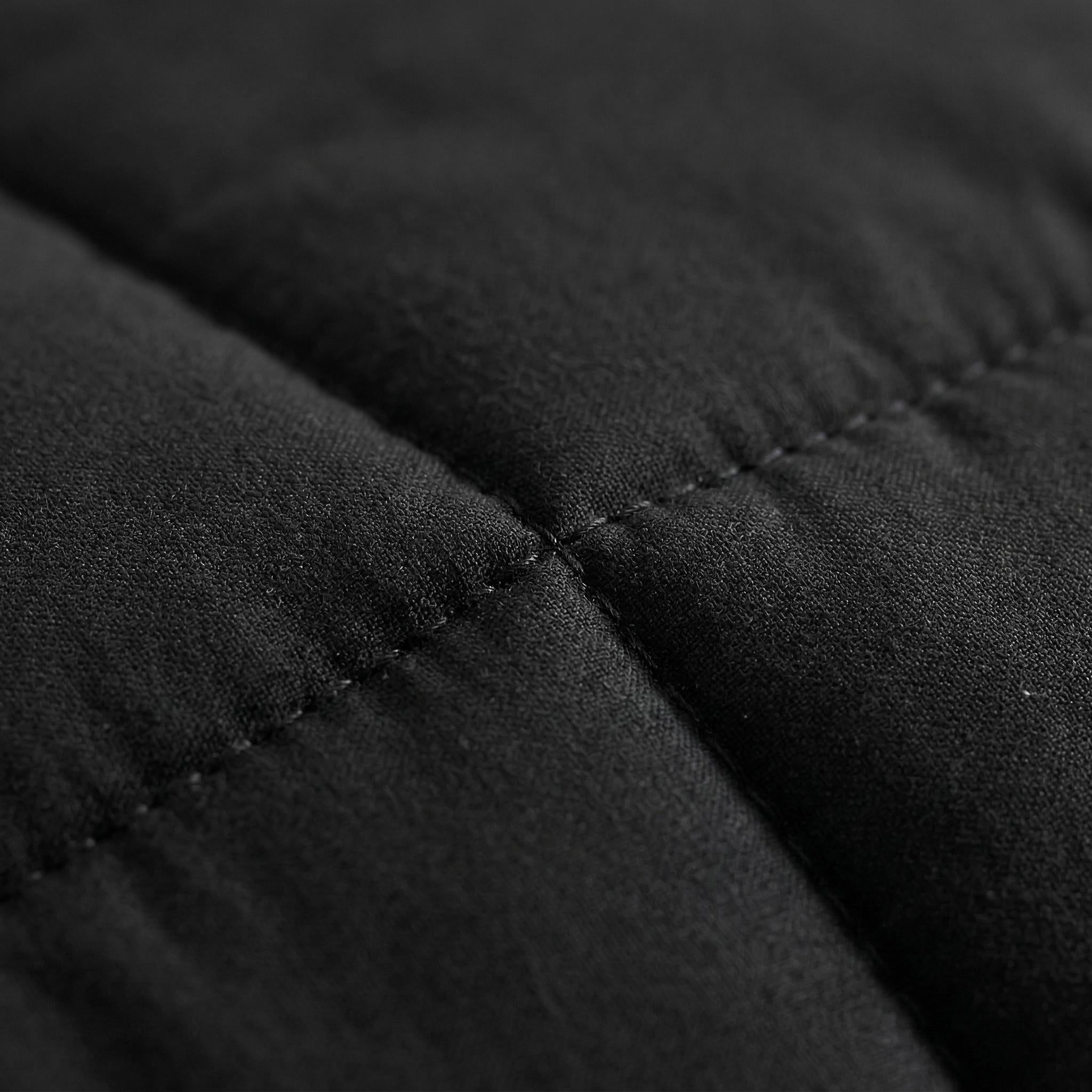 Close-up of a black microfiber comforter with visible box stitching and soft texture.