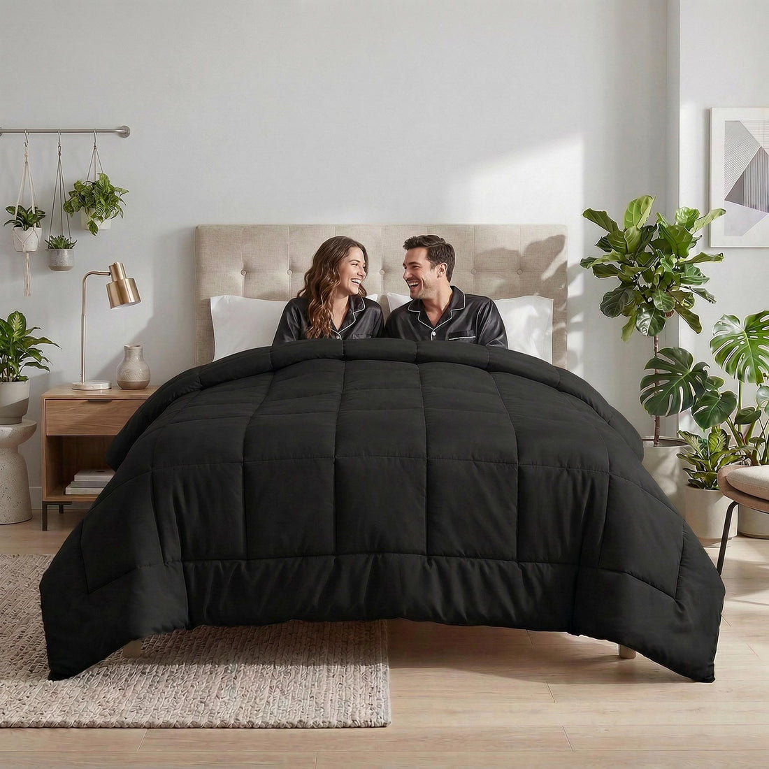 Couple smiling under a black microfiber all-season comforter with box stitching in a bedroom.