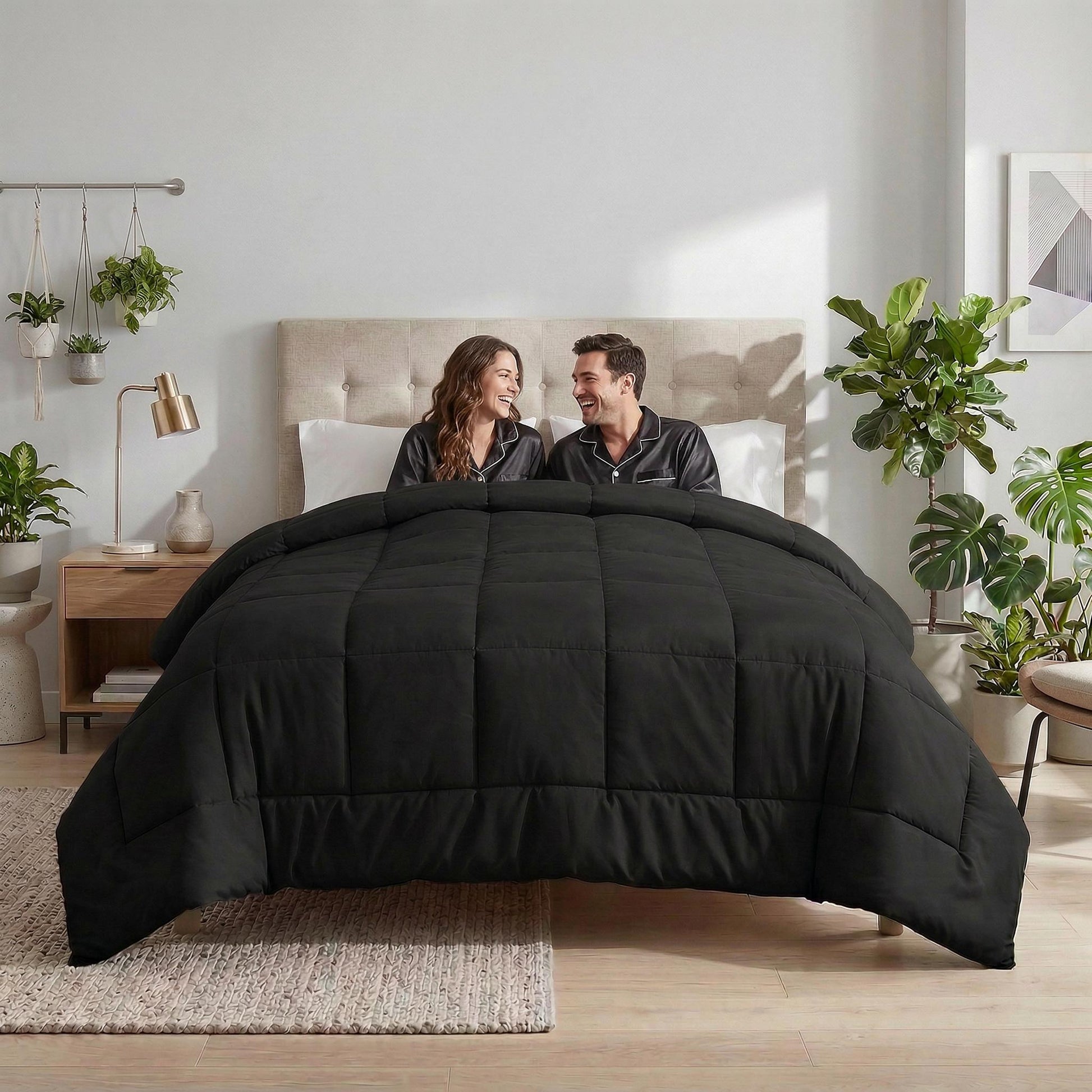 Couple smiling under a black microfiber all-season comforter with box stitching in a bedroom.
