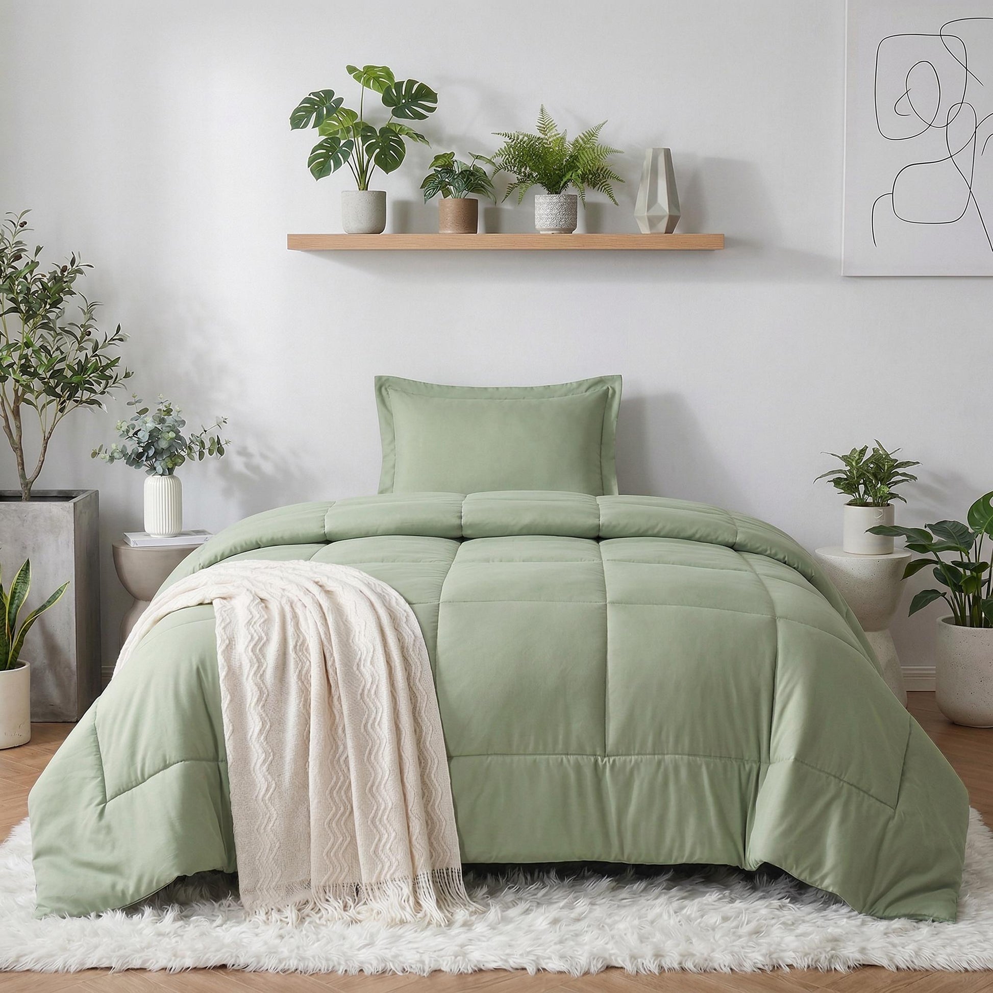 Sage green down alternative comforter with a simple checkered pattern and a cream throw blanket.