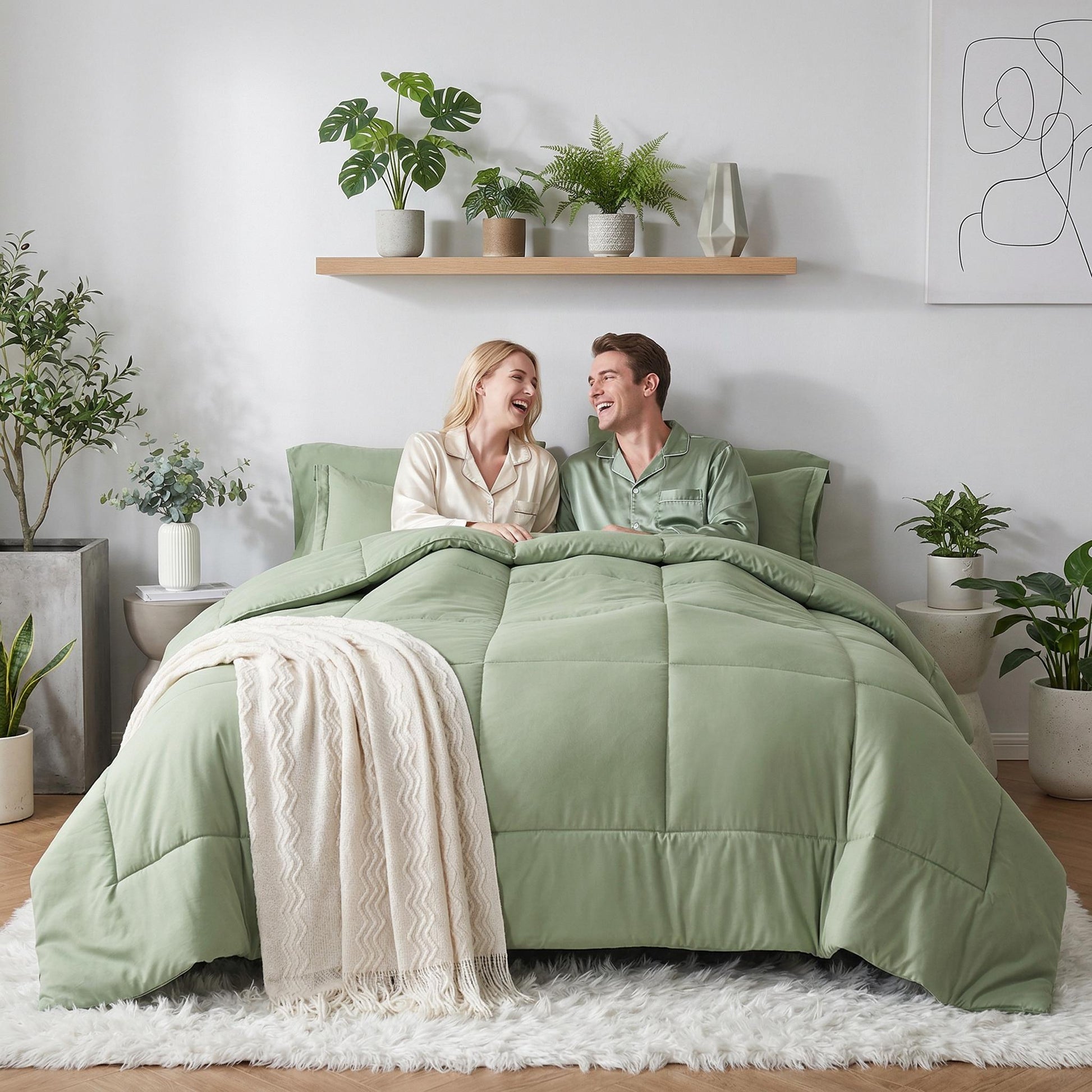 Couple on bed with a sage green down alternative duvet insert comforter set and a cream throw blanket.