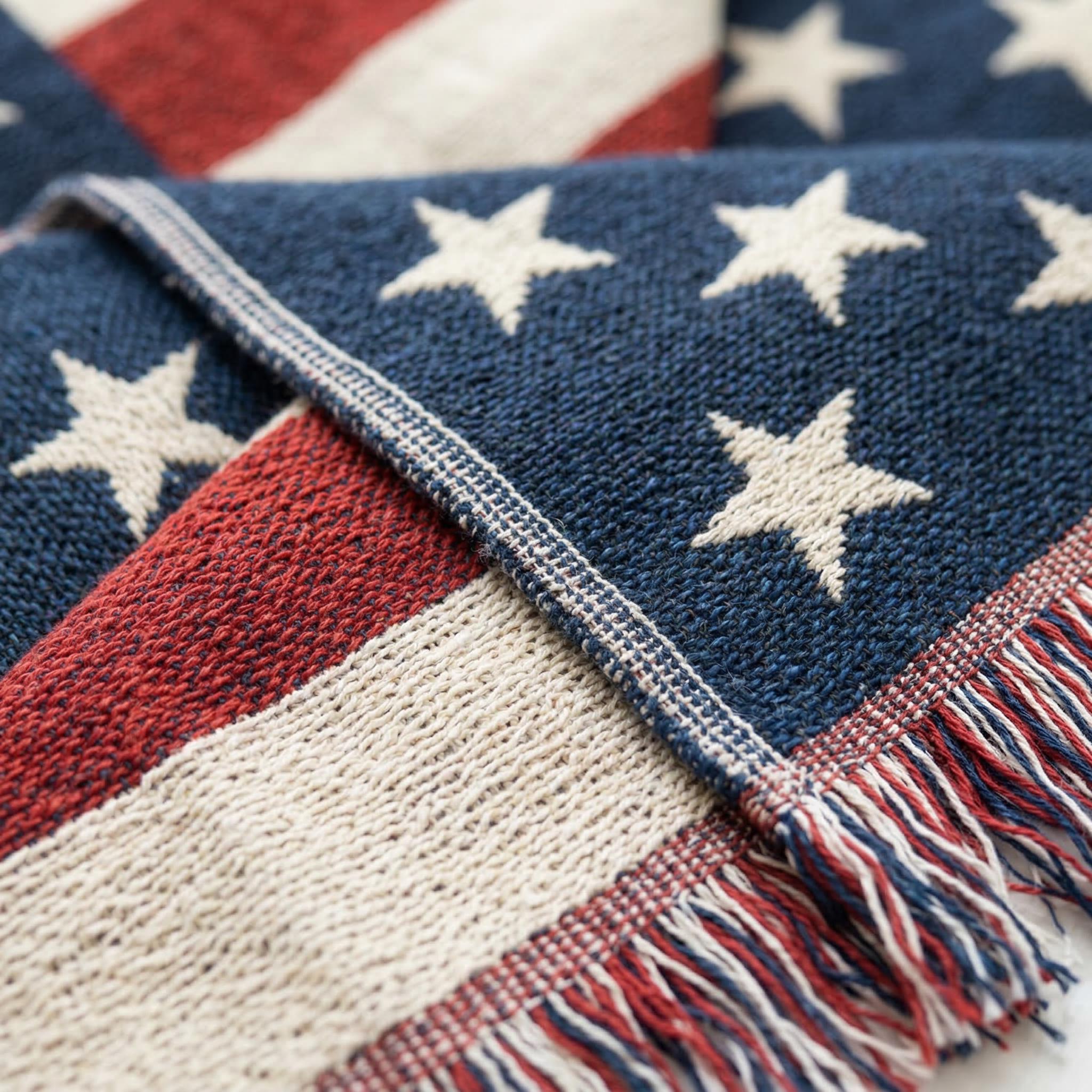 Knitted American flag throw blanket with red, white, and blue stripes, white stars, and fringe.
