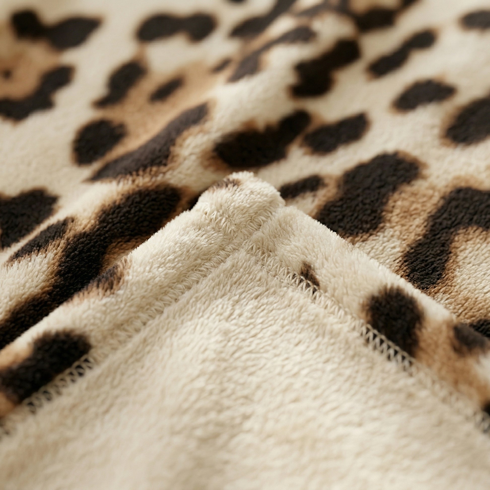 Close-up of a soft, reversible flannel blanket with a beige and brown leopard print pattern and cozy texture.
