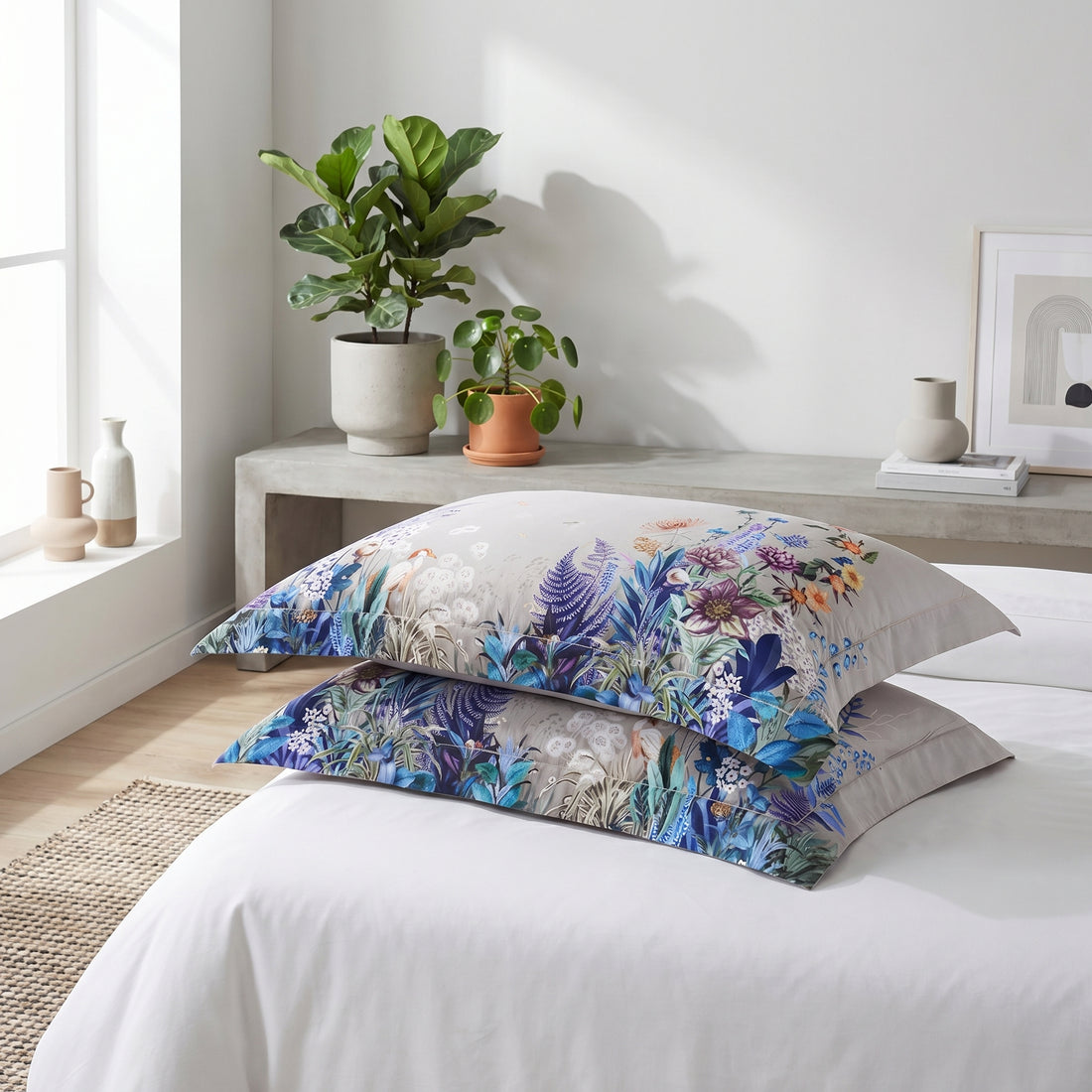 Woman in blue pajamas sitting on a beige cotton duvet set featuring a vibrant violet, blue, and sage floral botanical print.