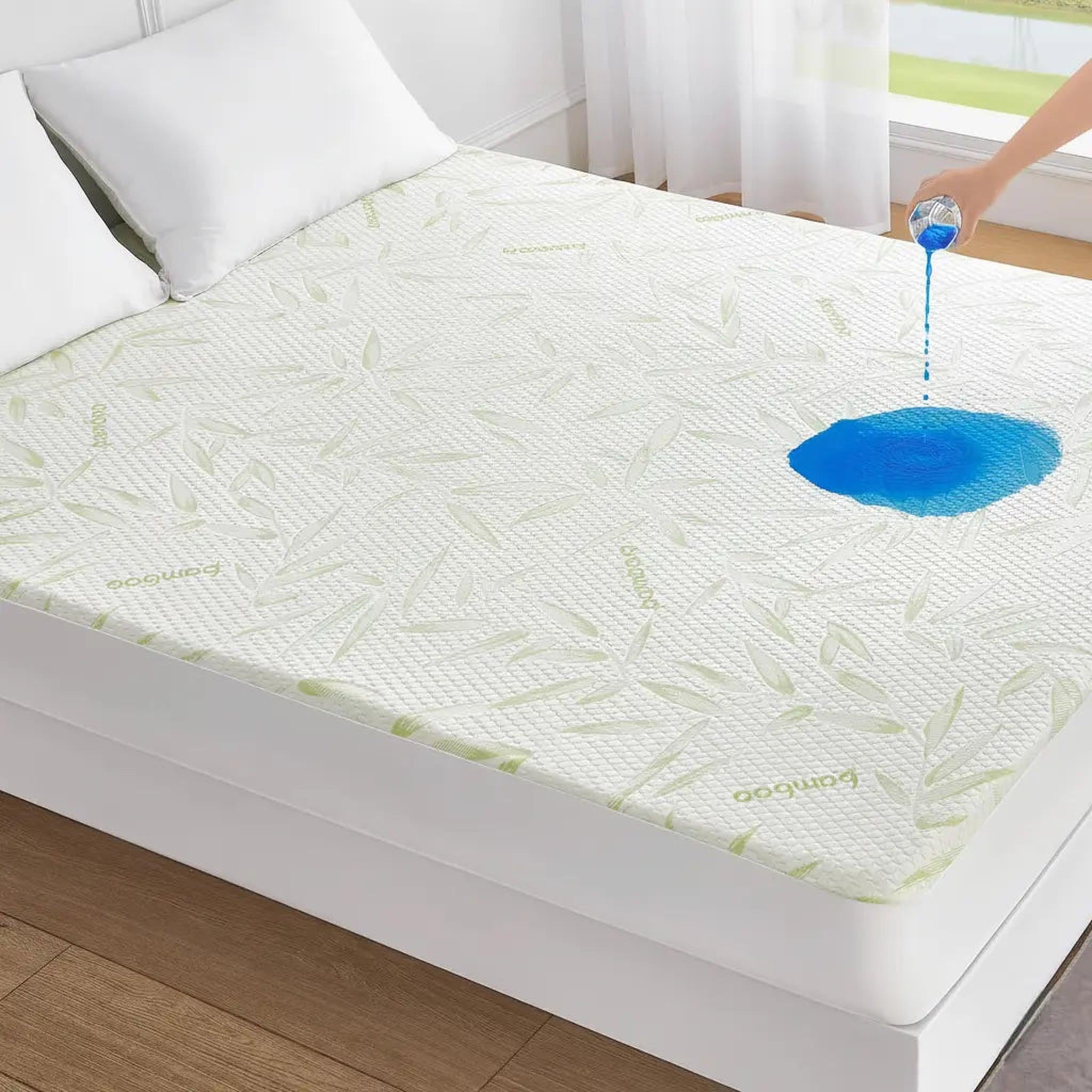 White bamboo fiber mattress protector with green leaf pattern, showing a blue liquid spill being repelled.