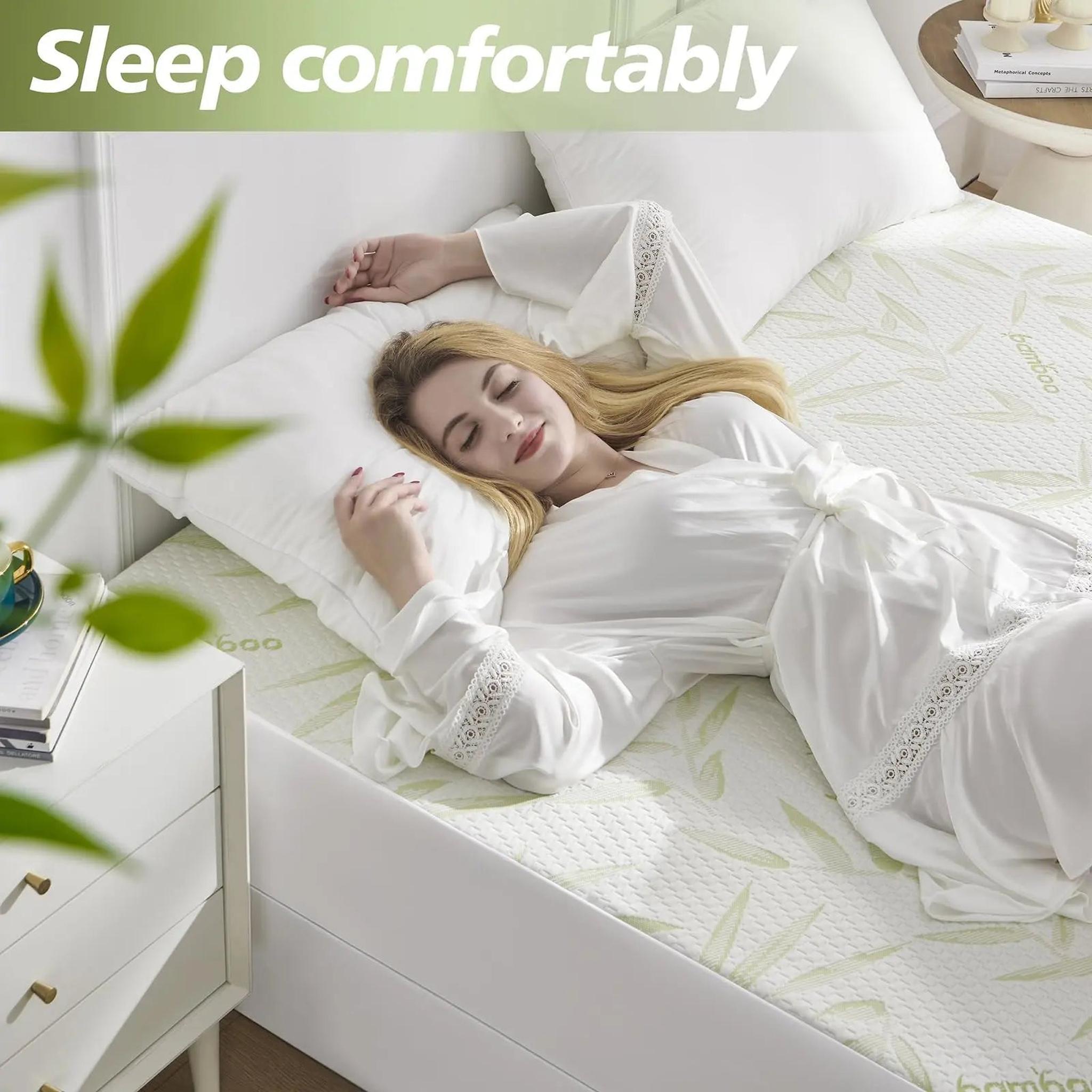 Woman sleeping soundly on a white bamboo fiber mattress protector with green leaf patterns.