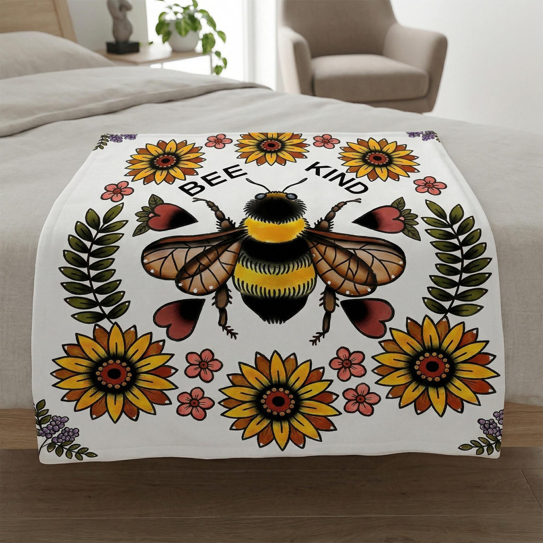Blonde woman wrapped in a white plush blanket with a large "Bee Kind" bee and sunflower floral print.