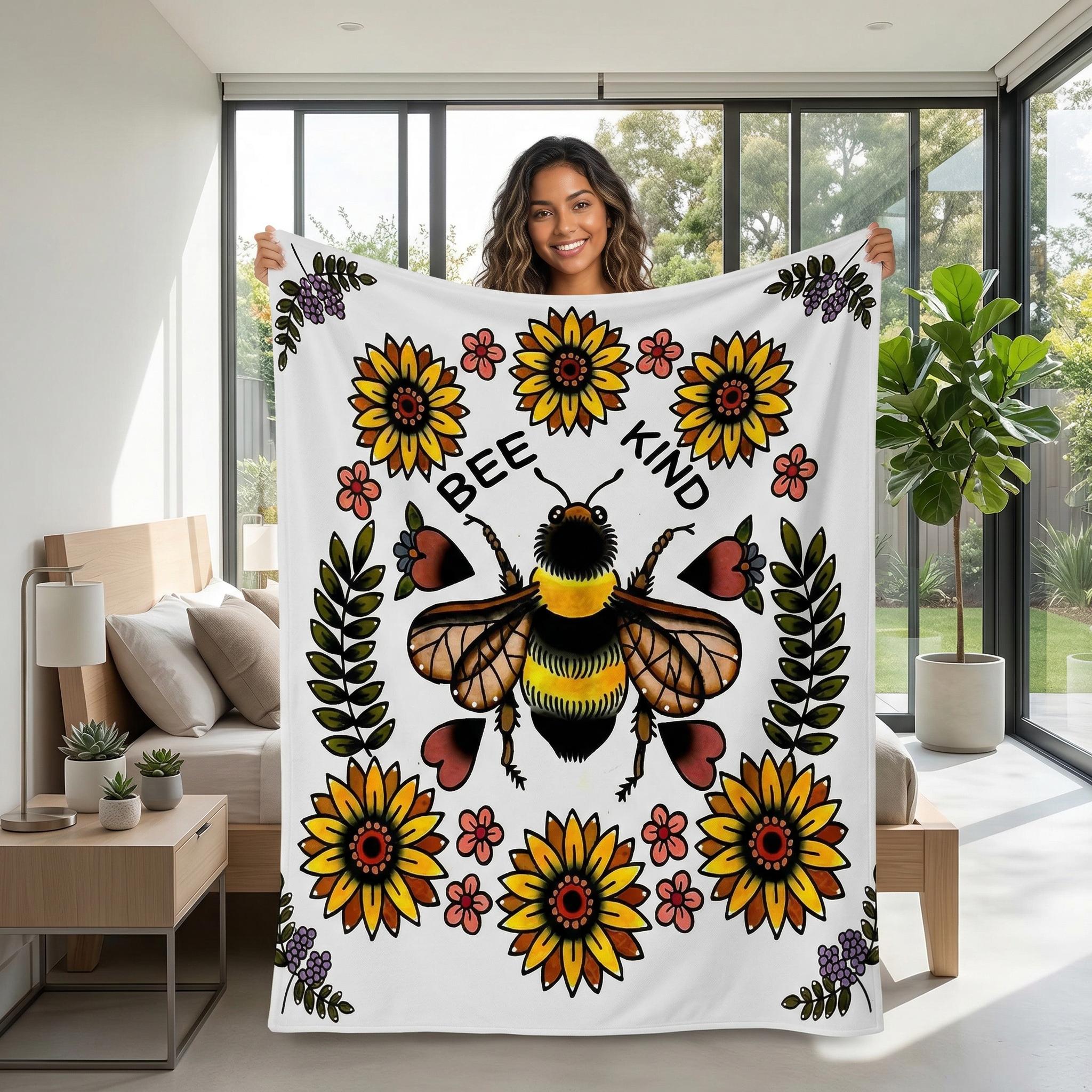 Woman holding a white plush blanket with a large "Bee Kind" bee and sunflower floral print.