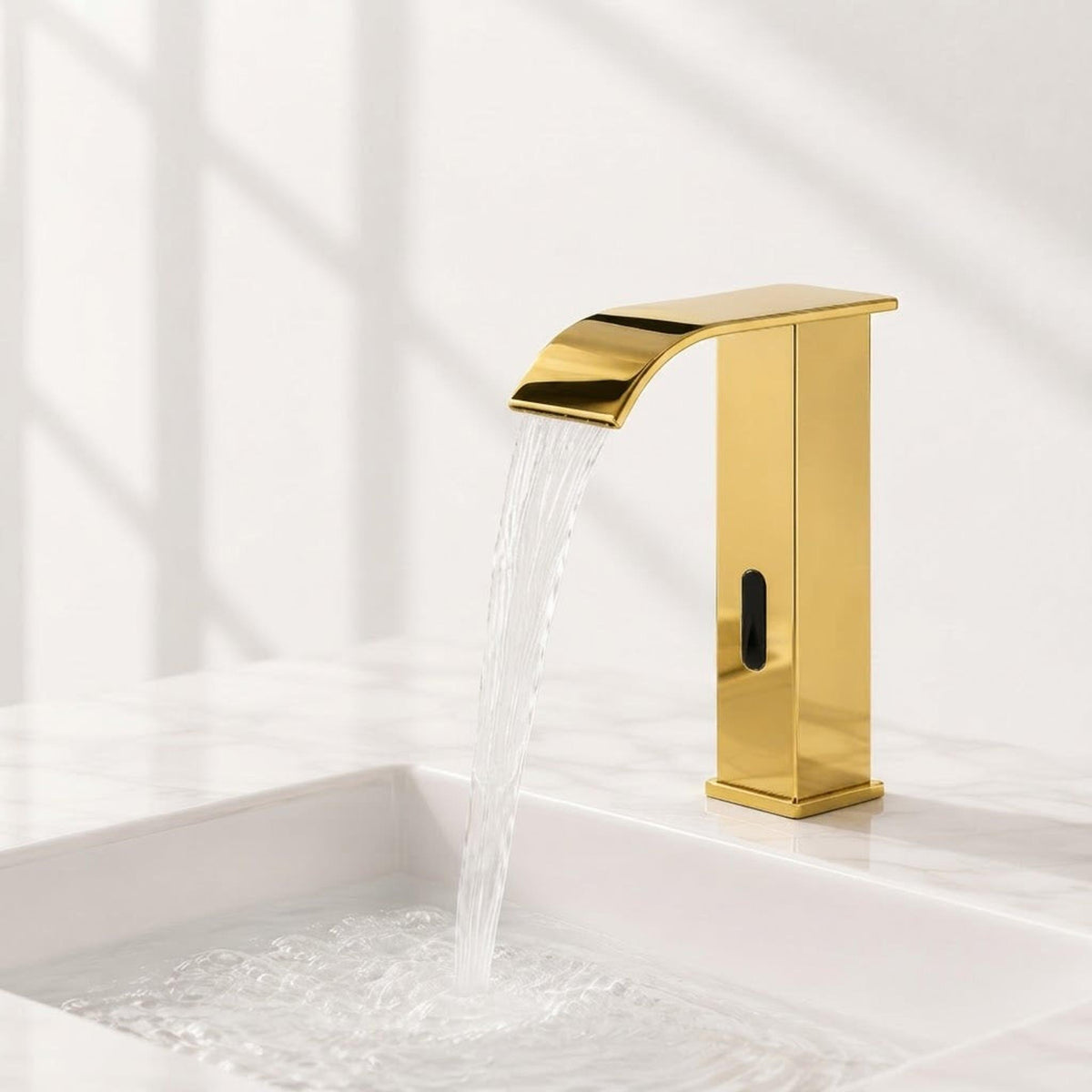 Modern gold touchless bathroom faucet with a waterfall spout and automatic sensor installed on a white marble sink.