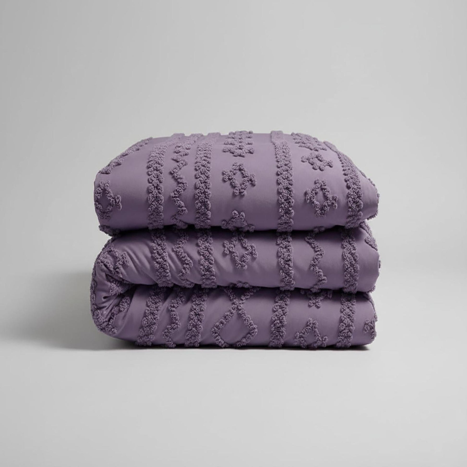 Folded queen size Boho Comforter Set in soft tufted lavender cotton polyester, featuring a textured geometric design.