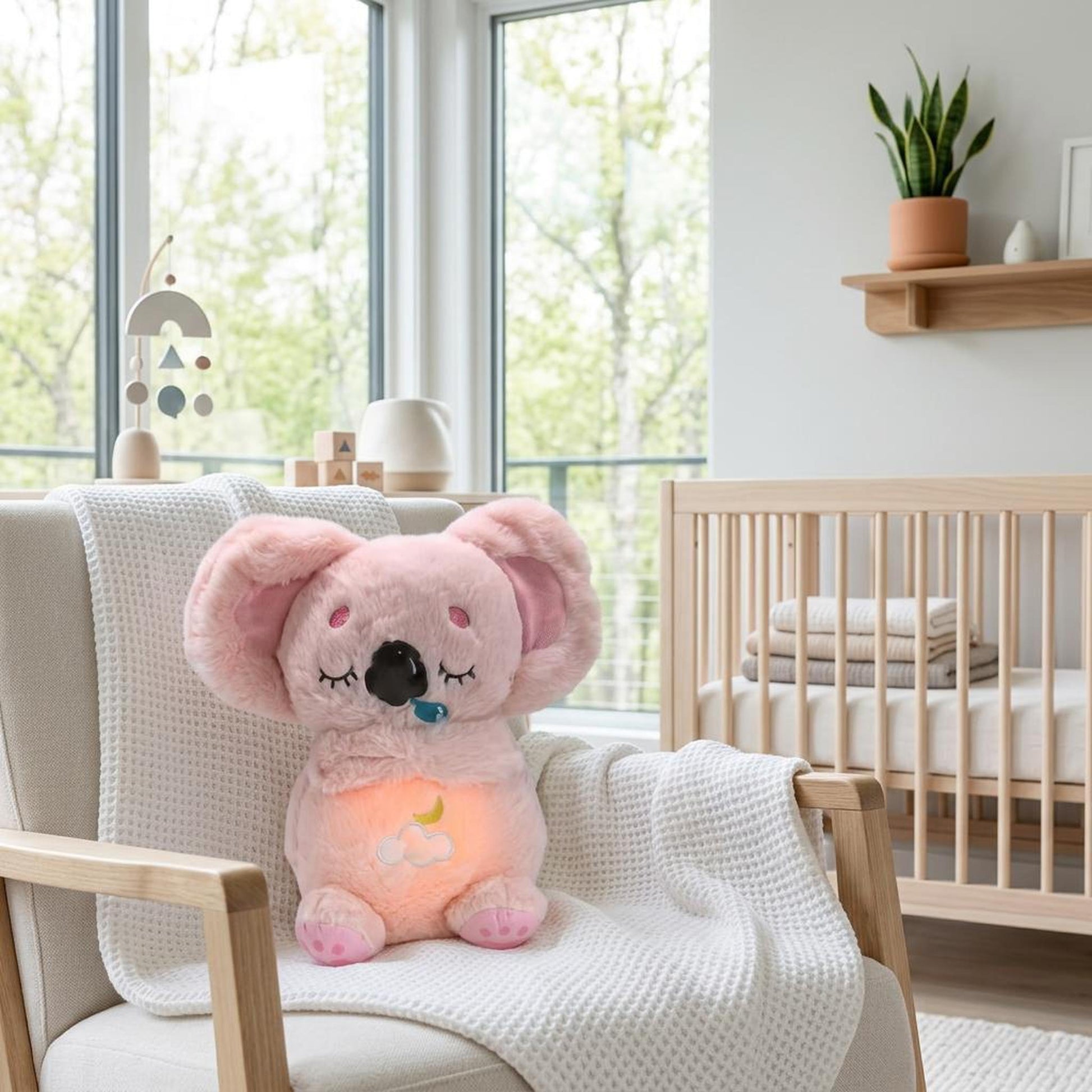 Pink plush koala toy with a glowing belly sitting on an armchair in a nursery.