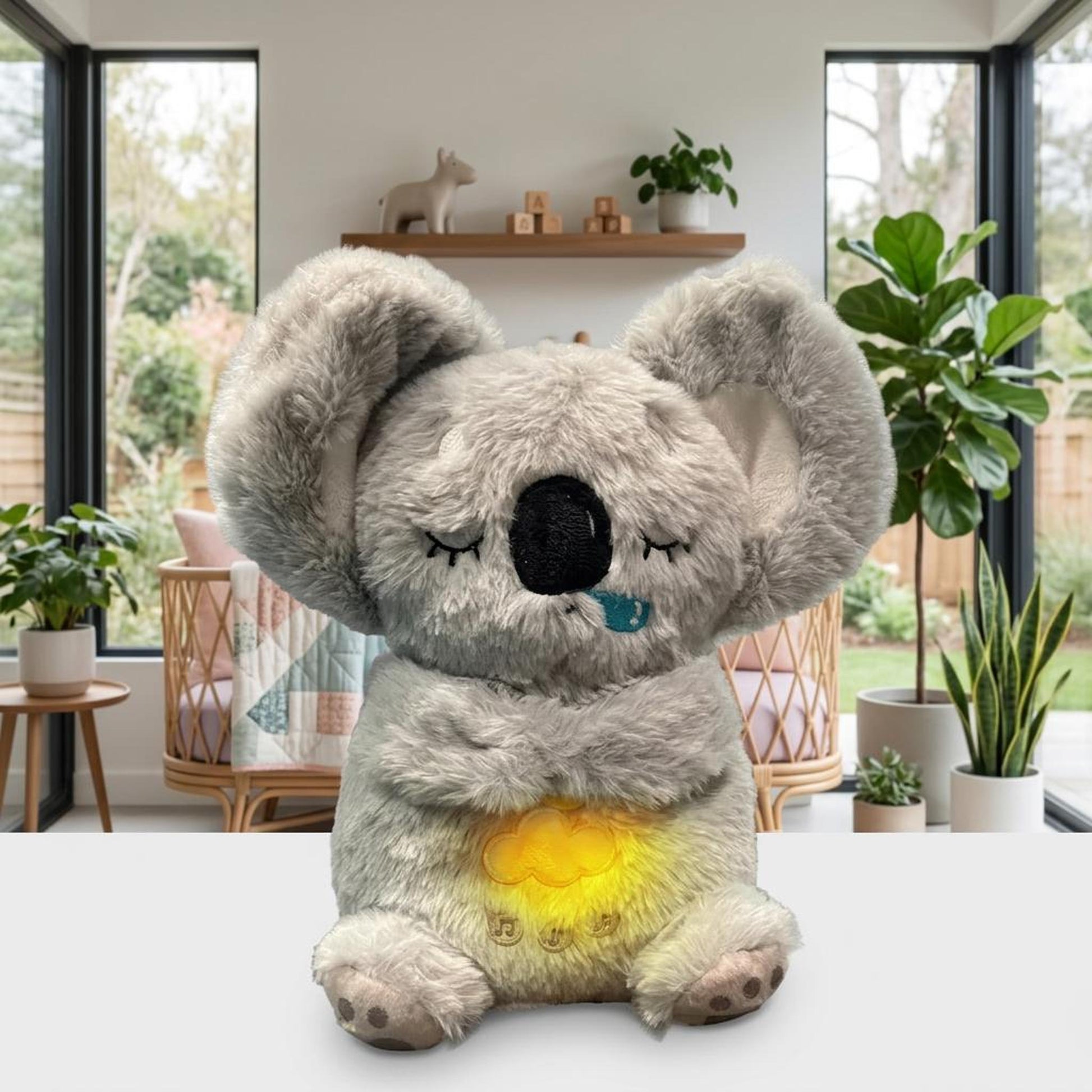 Plush grey koala toy with a glowing yellow belly in a bright nursery.
