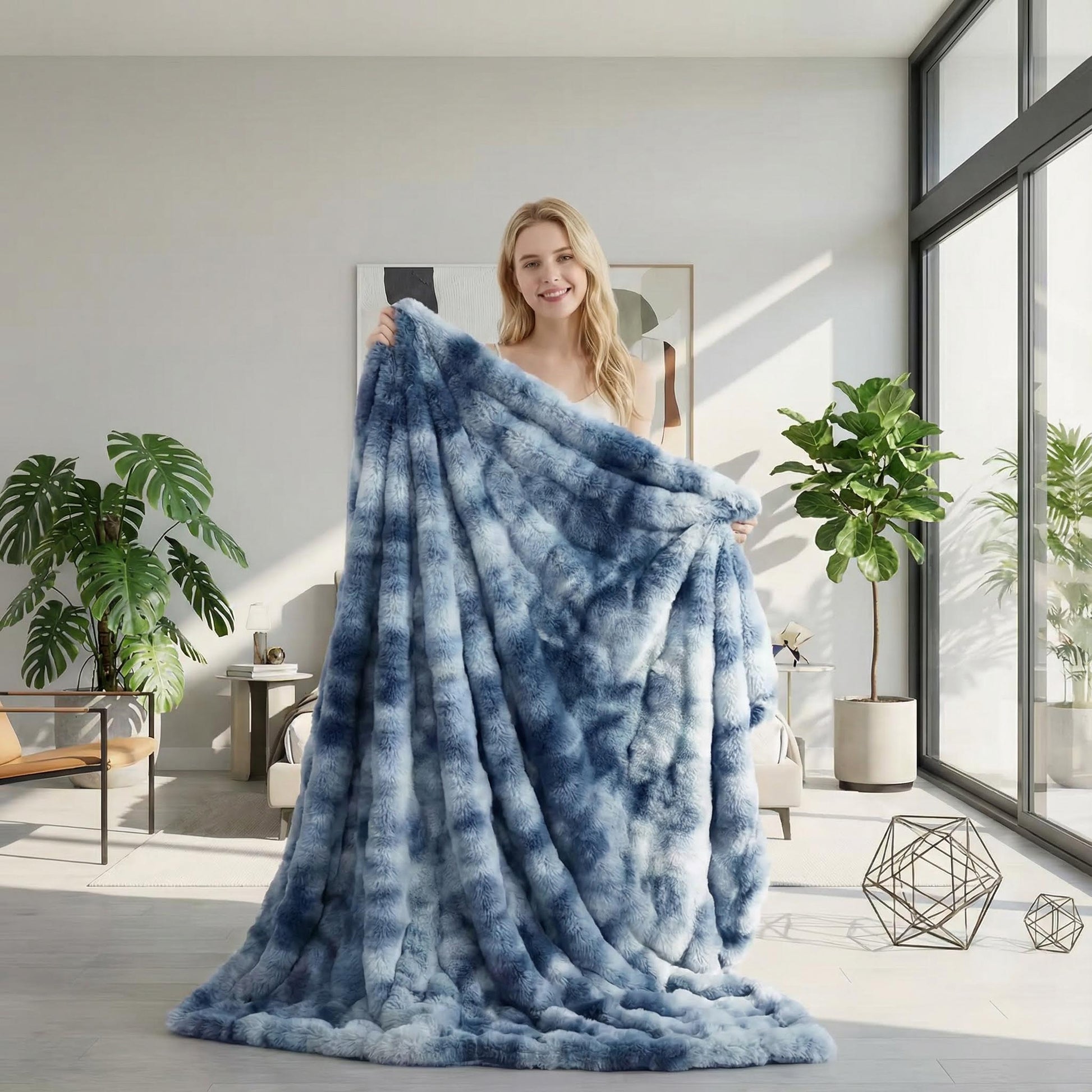 Smiling woman holding a large, fluffy blue and white tie-dye bubble plush throw blanket in a bright living room.