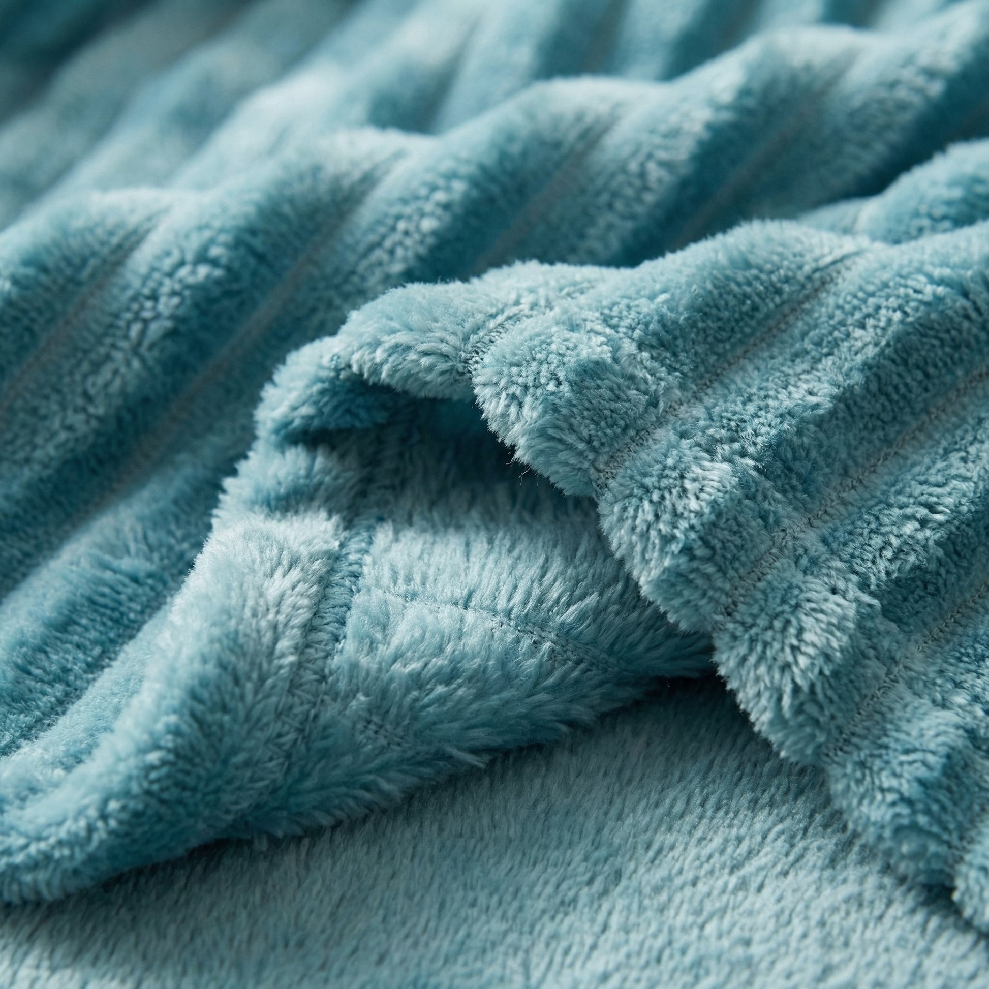 Close-up of a soft, teal coral velvet flannel blanket with a ribbed texture.
