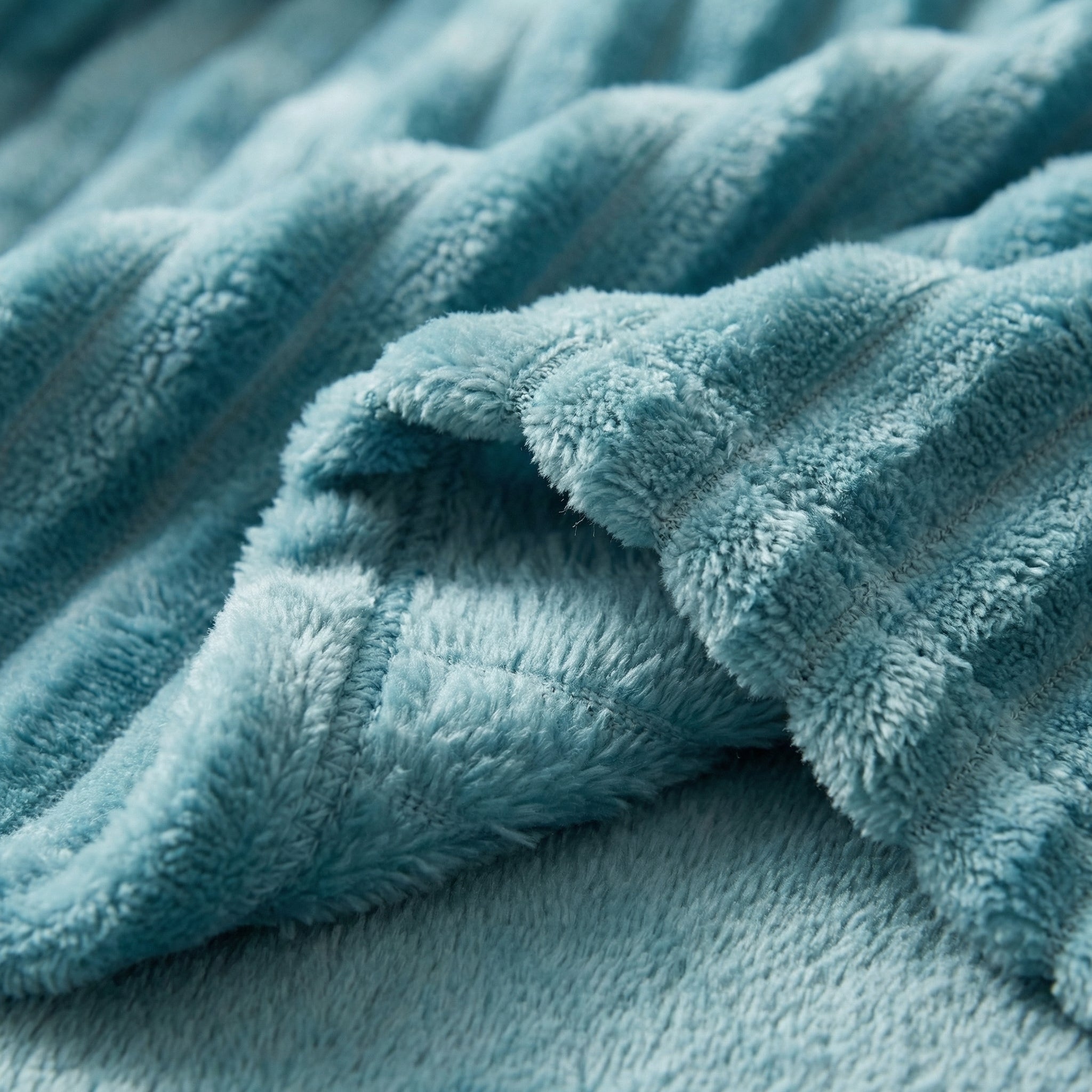 Close-up of a soft, teal coral velvet flannel blanket with a ribbed texture.