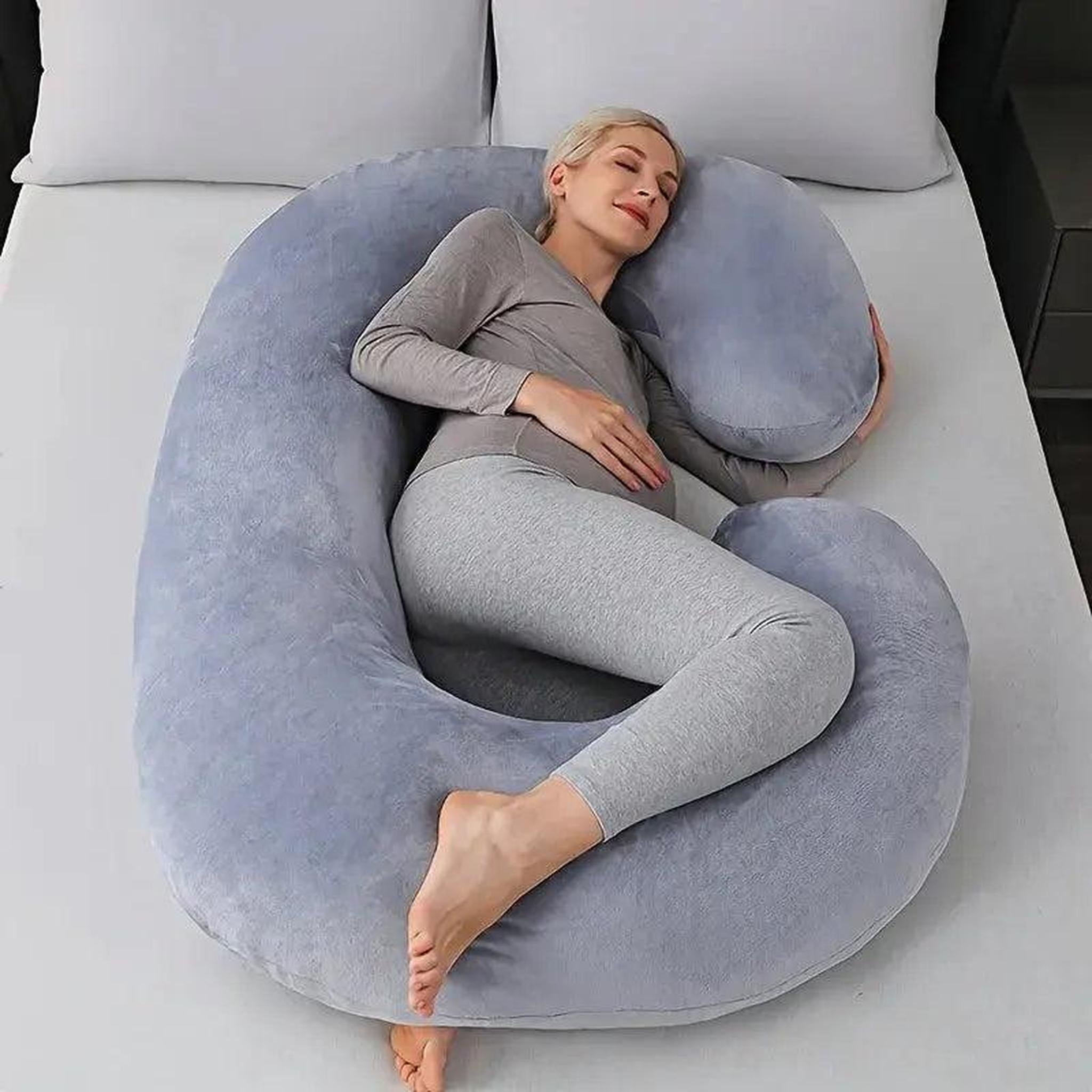 Woman sleeping peacefully on a large gray C-shaped support pillow with plush cushioning.