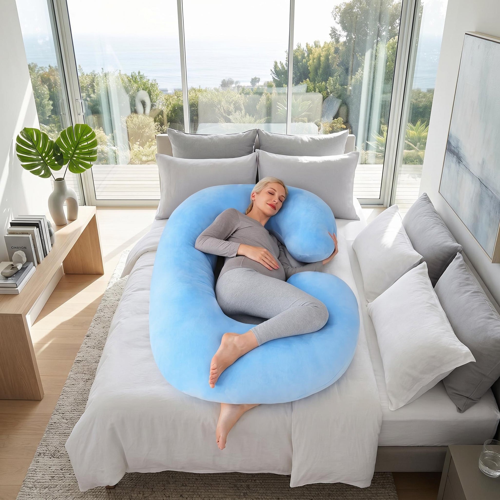Woman resting comfortably on a large, light blue C-shaped support pillow in a modern bedroom.
