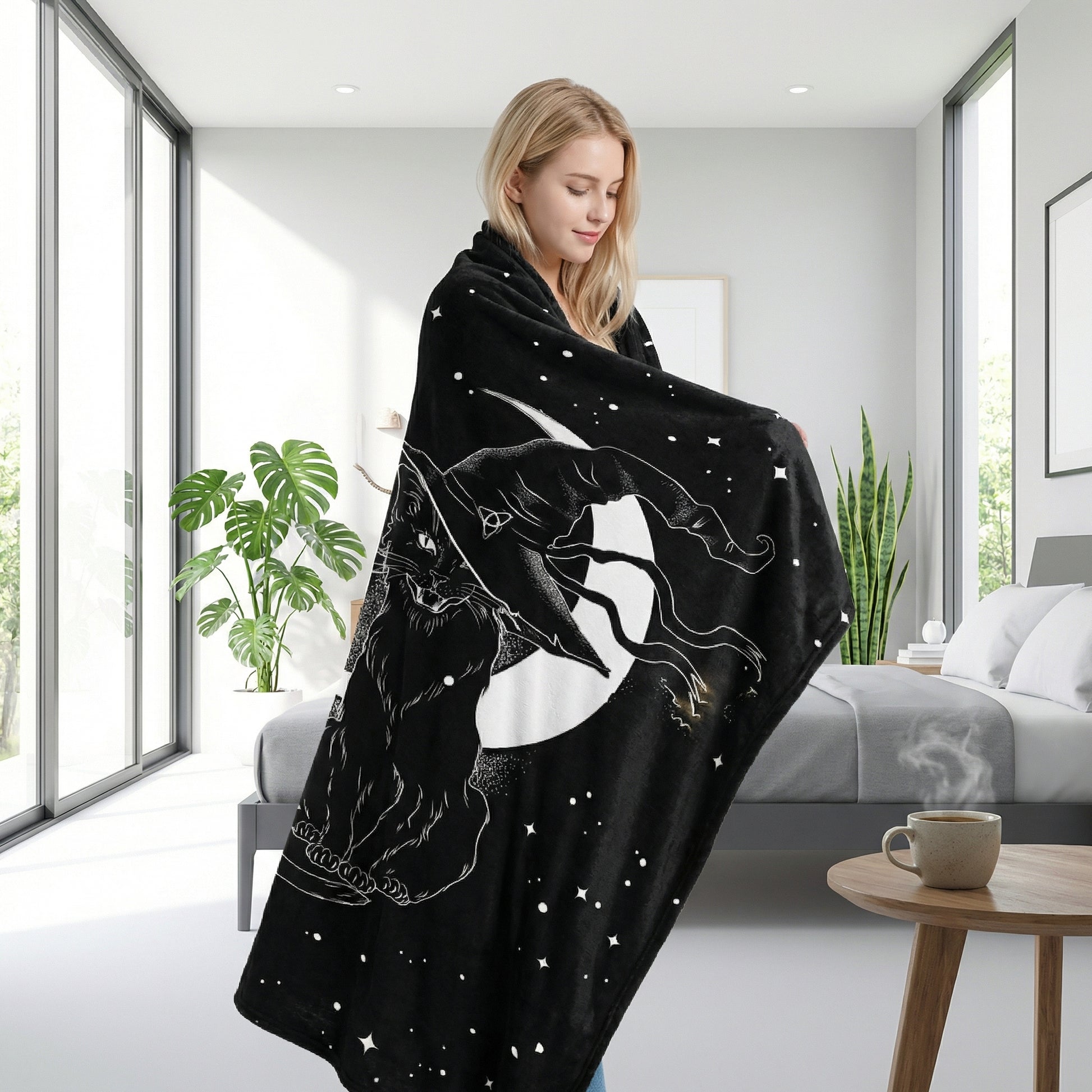 Black flannel throw blanket with white cat and moon 3D print, draped over a woman in a modern bedroom.