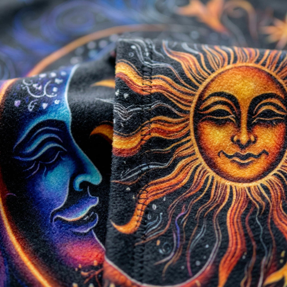 Woman wrapped in a black Celestial Dreams throw blanket with a vibrant sun and moon design.