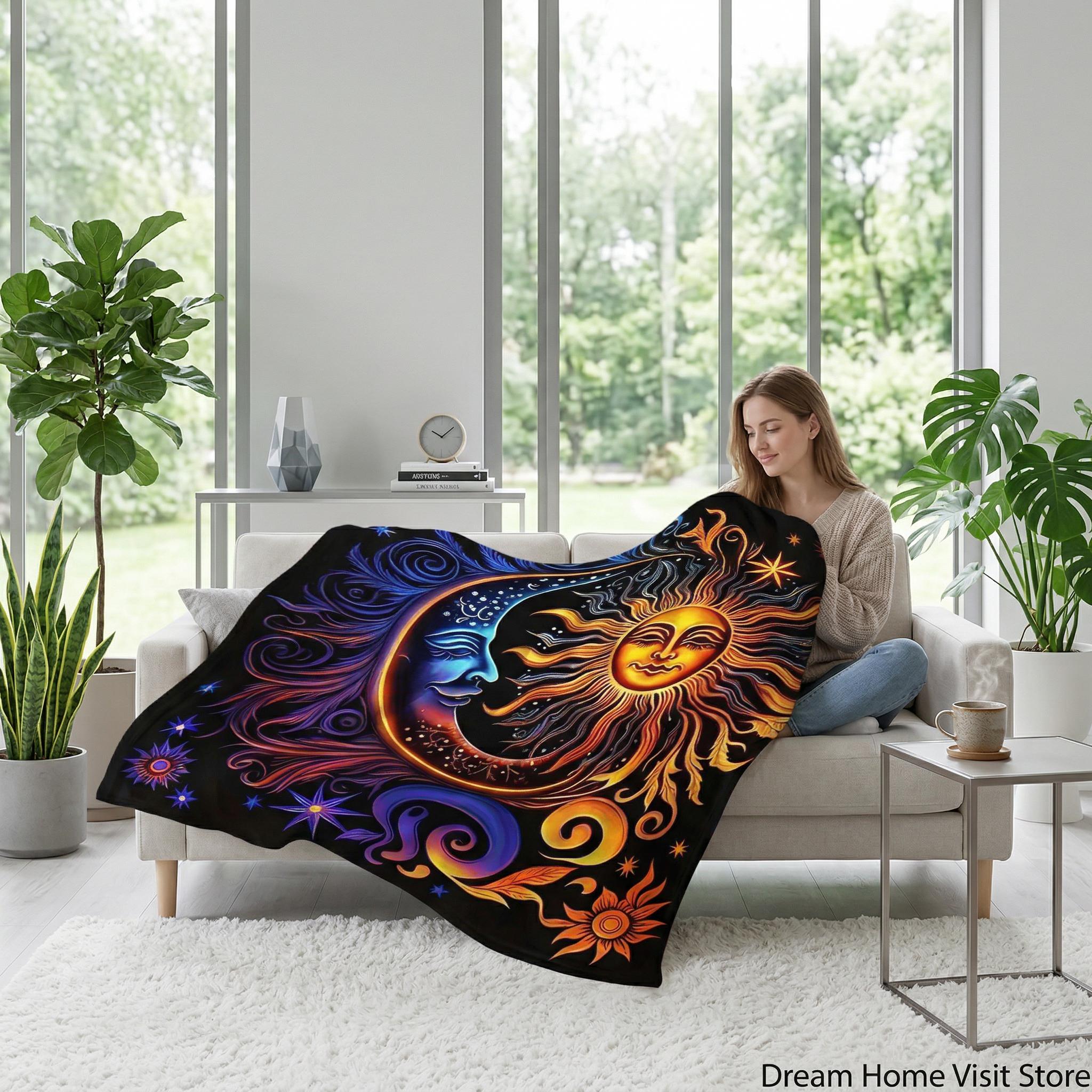Woman on a sofa with a black Celestial Dreams Throw Blanket featuring a vibrant sun and moon design.