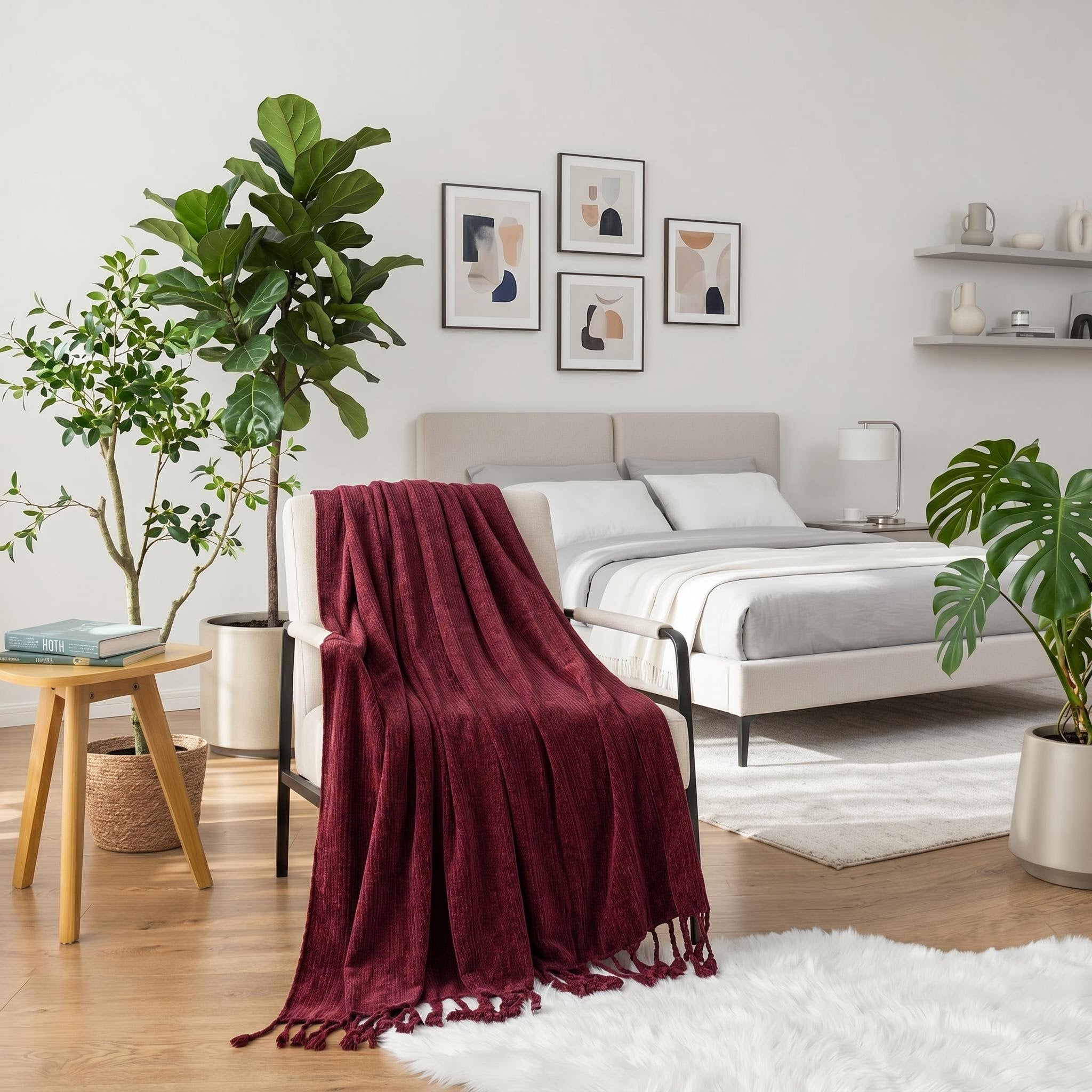 Red chenille throw blanket with fringe tassels draped over a cream armchair in a bright bedroom.