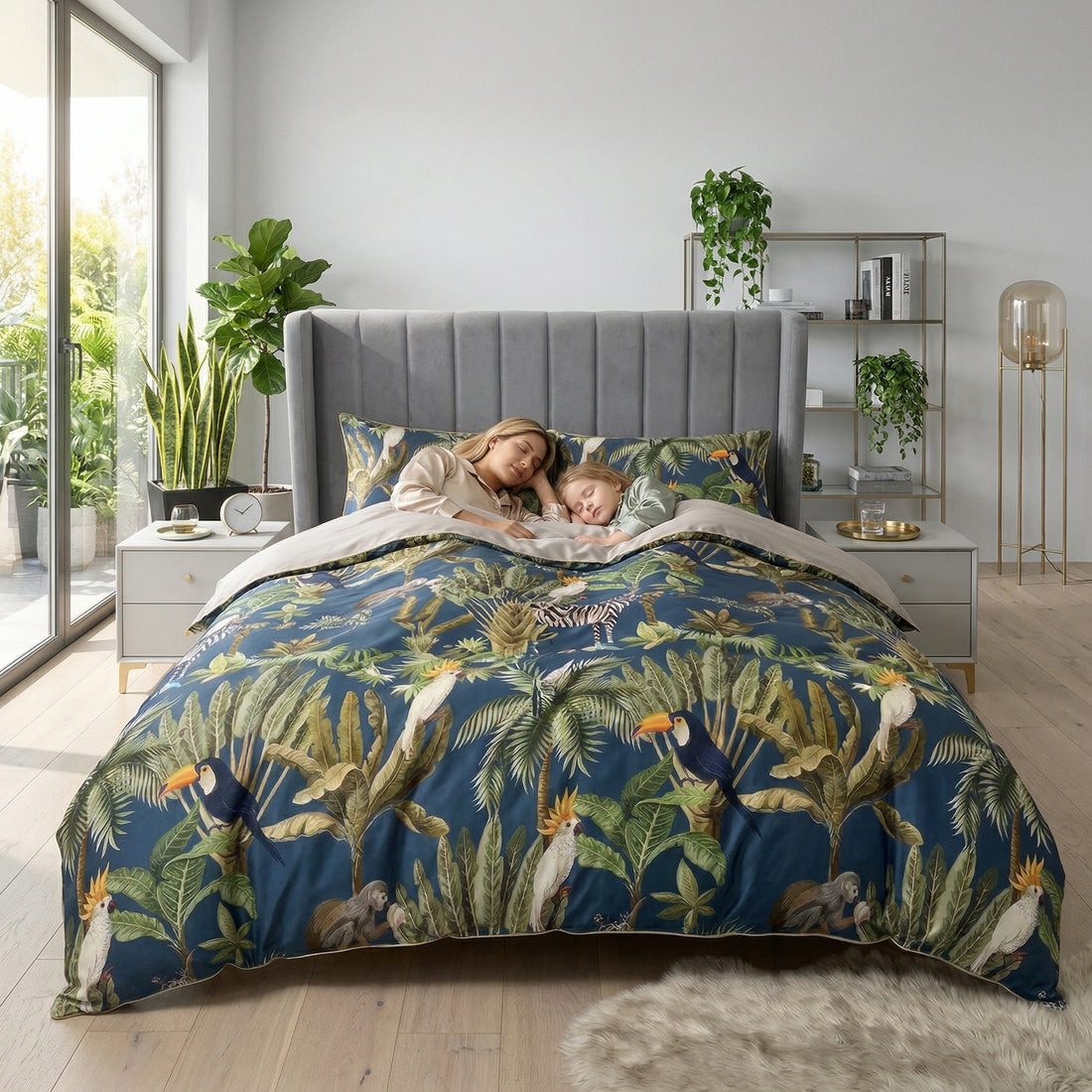 King size bed with blue tropical duvet cover set, featuring toucans, monkeys, and palm leaves, with a woman and child sleeping.