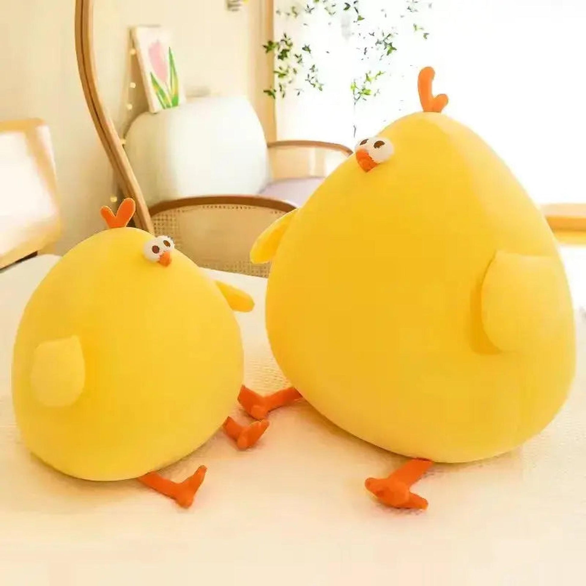 Two bright yellow, round plush chicken pillows, one large and one small, with orange feet and tiny eyes.