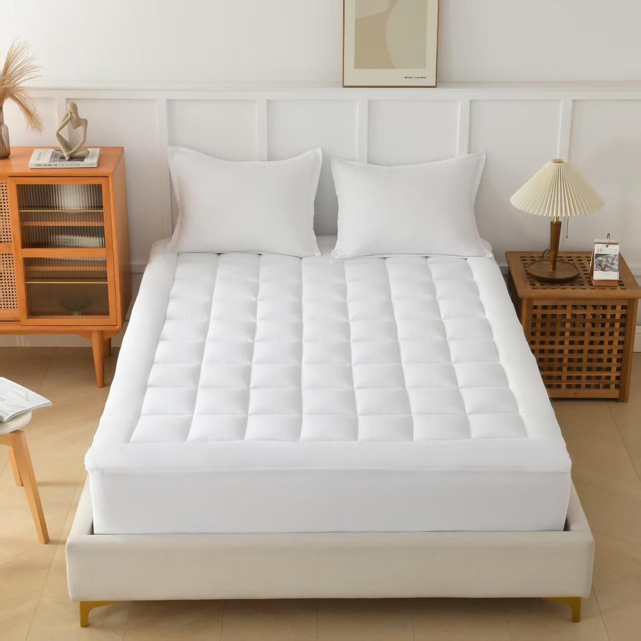 White quilted CloudLift Cooling Mattress Topper on a bed with two pillows in a bedroom setting.