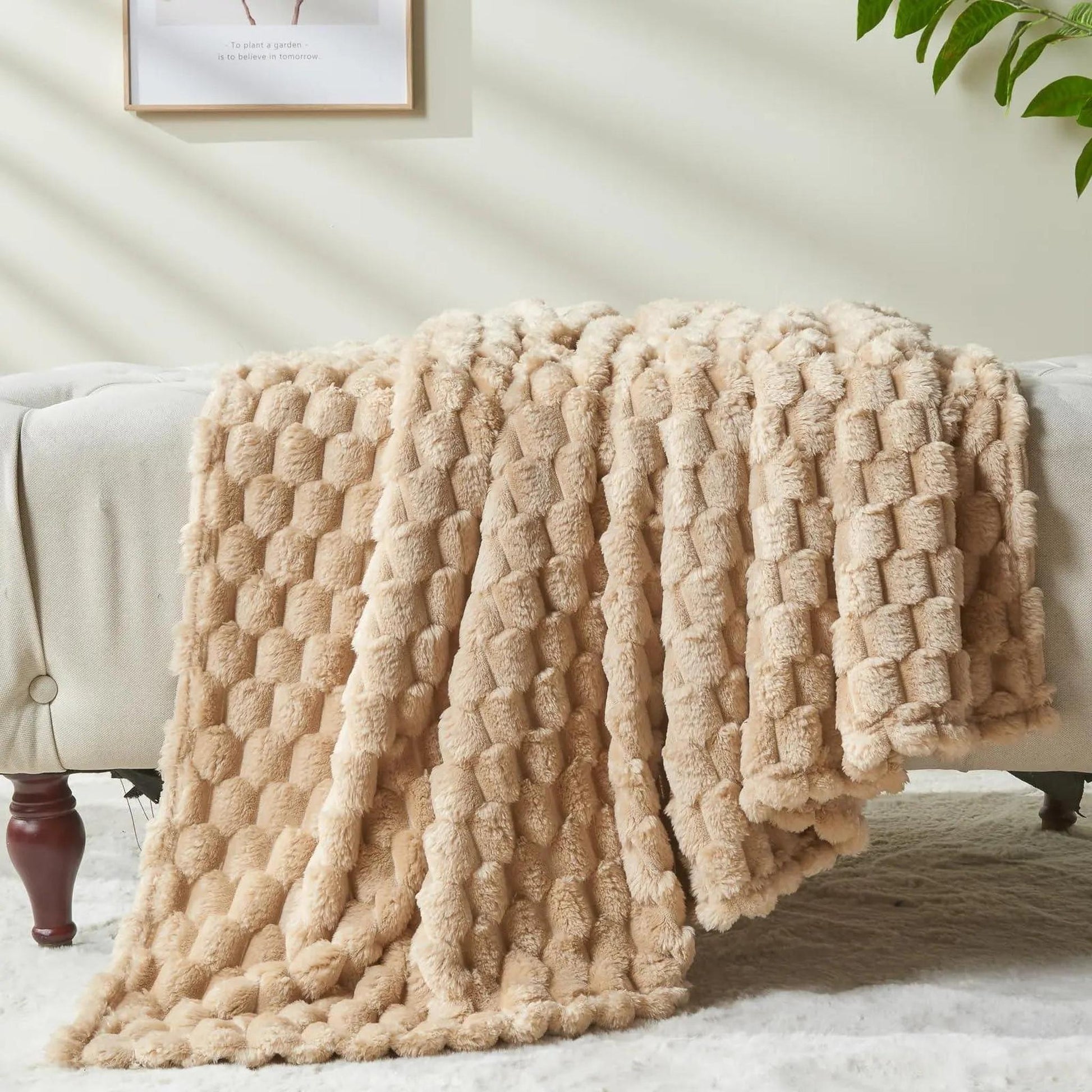 Beige Clouds Jacquard Fleece Blanket draped over a sofa, showing its soft, textured 3D cloud pattern.