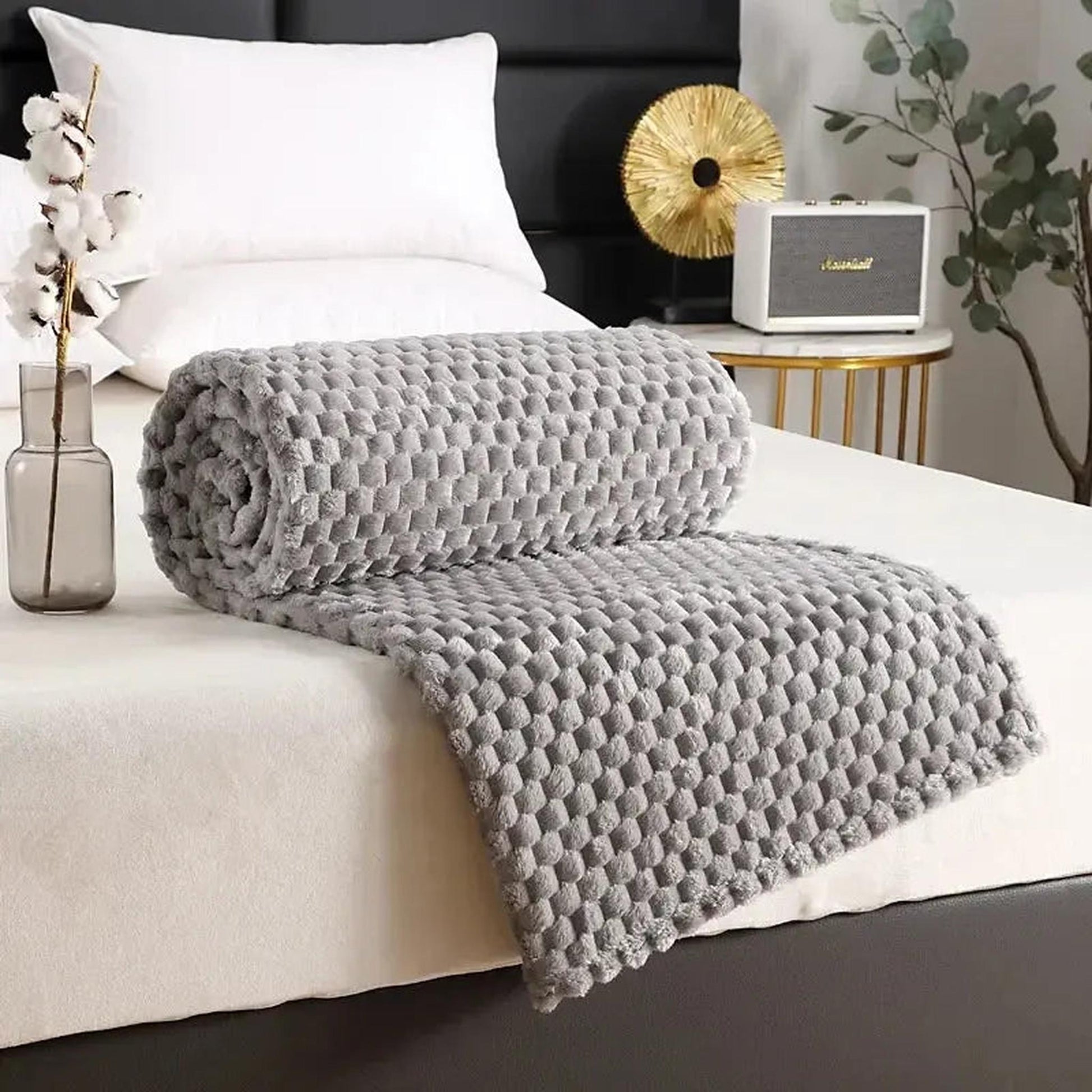 Gray silky flannel fleece blanket with a 3D cloud jacquard pattern, rolled on a bed.