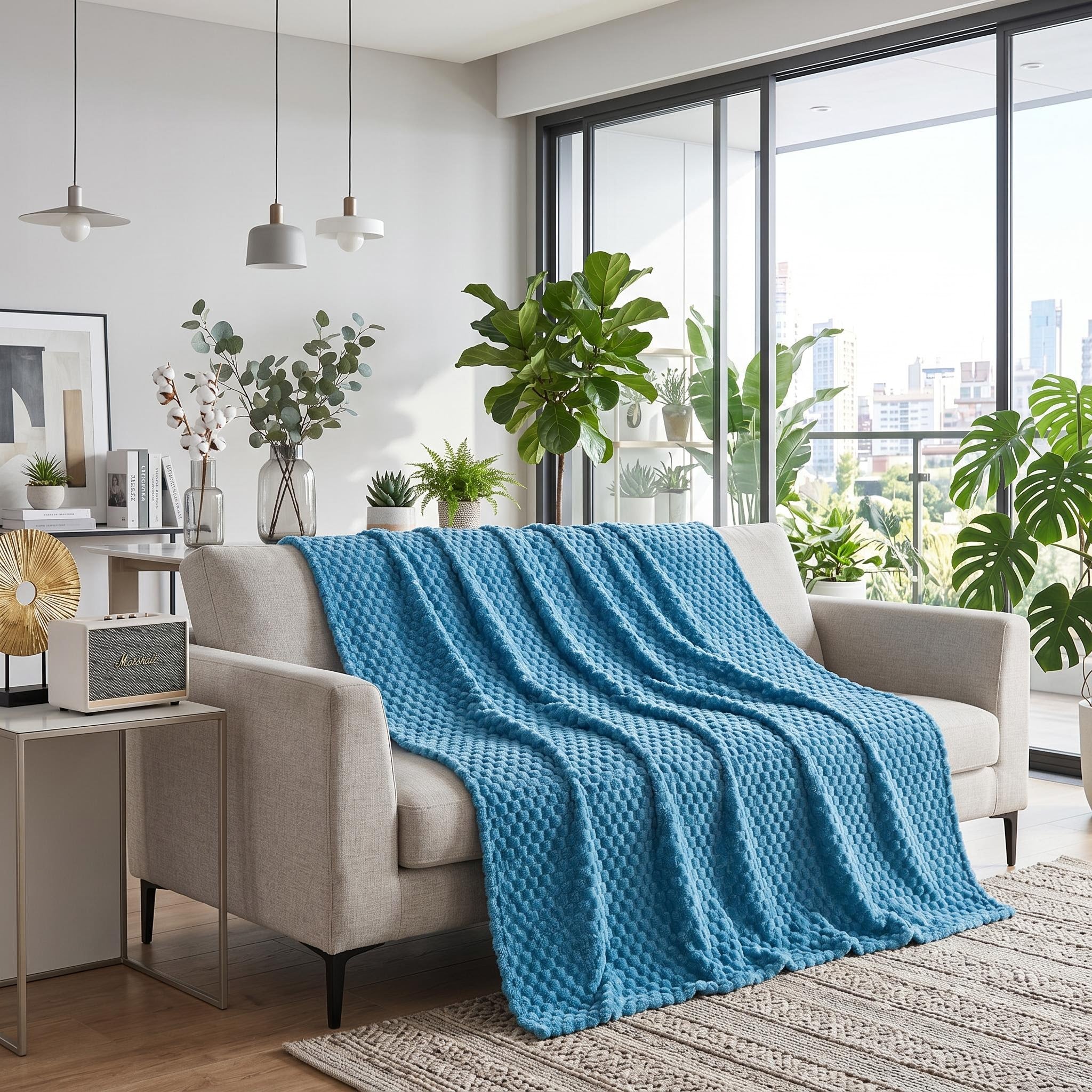 Blue jacquard fleece blanket with 3D cloud pattern draped over a light sofa in a modern living room.