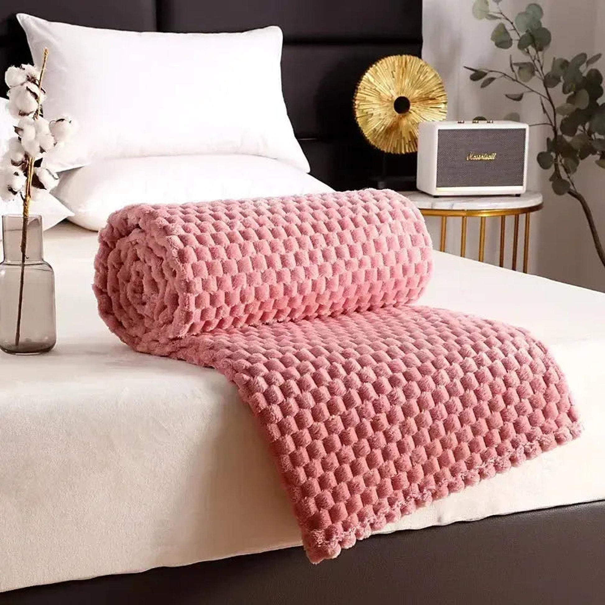 Pink Clouds Jacquard Fleece Blanket, rolled and draped on a bed, showcasing its soft 3D cloud texture.