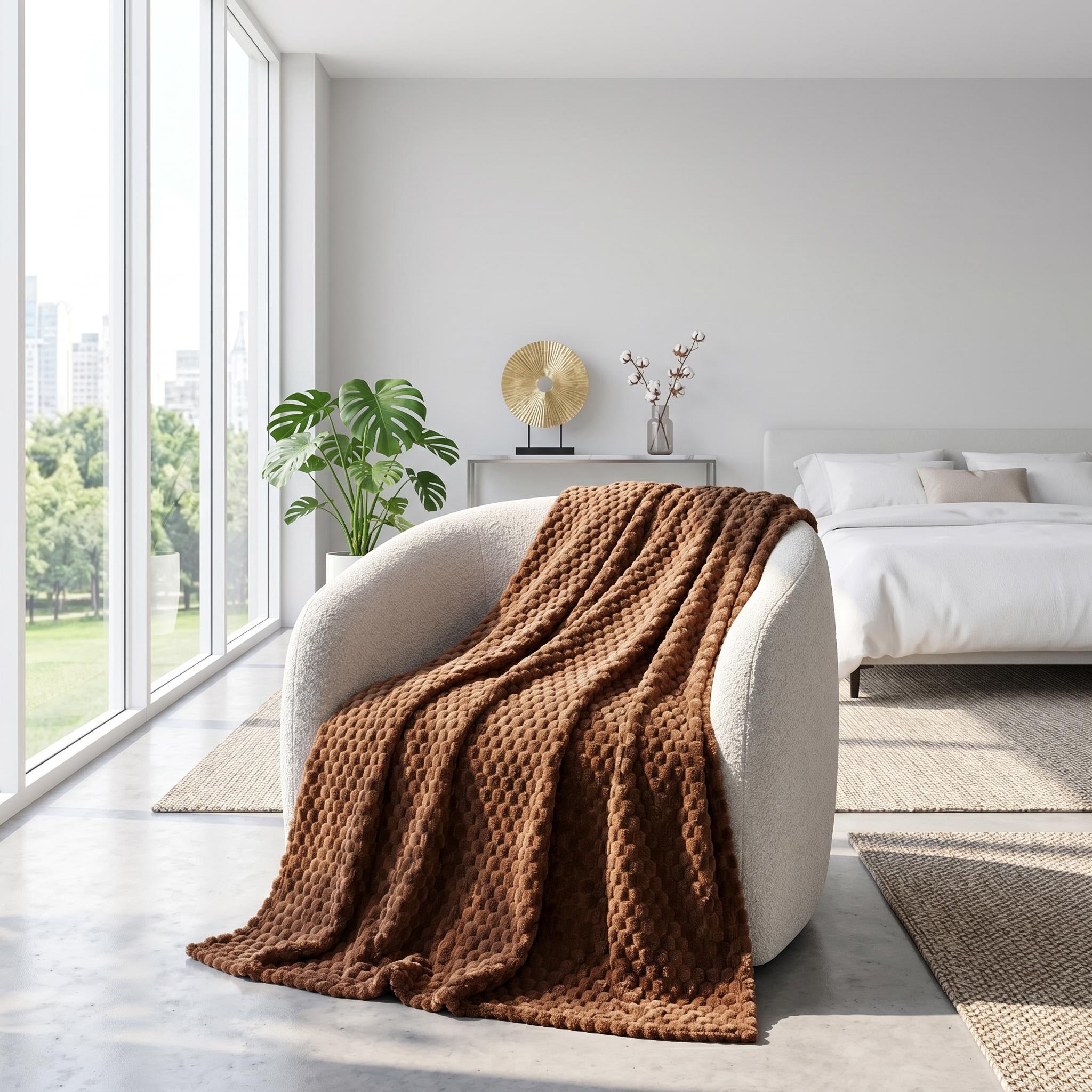Brown Clouds Jacquard Fleece Blanket draped over a cream armchair in a bright, modern bedroom.