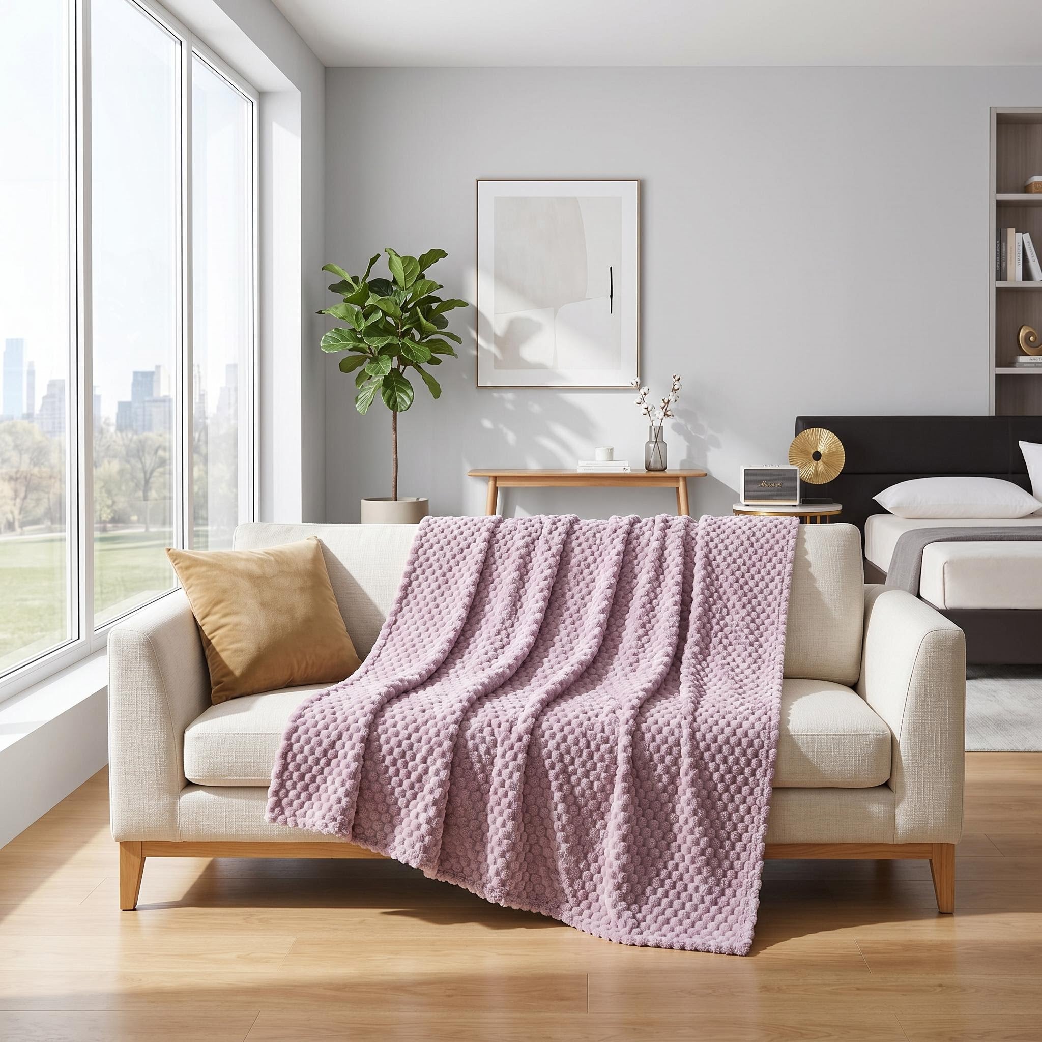 Soft pink jacquard fleece blanket with a 3D cloud pattern draped over a cream sofa.