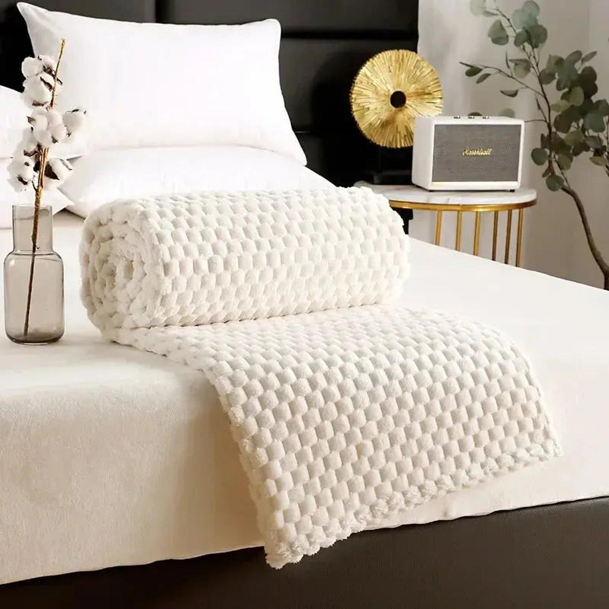 White silky flannel fleece blanket with a 3D cloud jacquard pattern, rolled on a bed.
