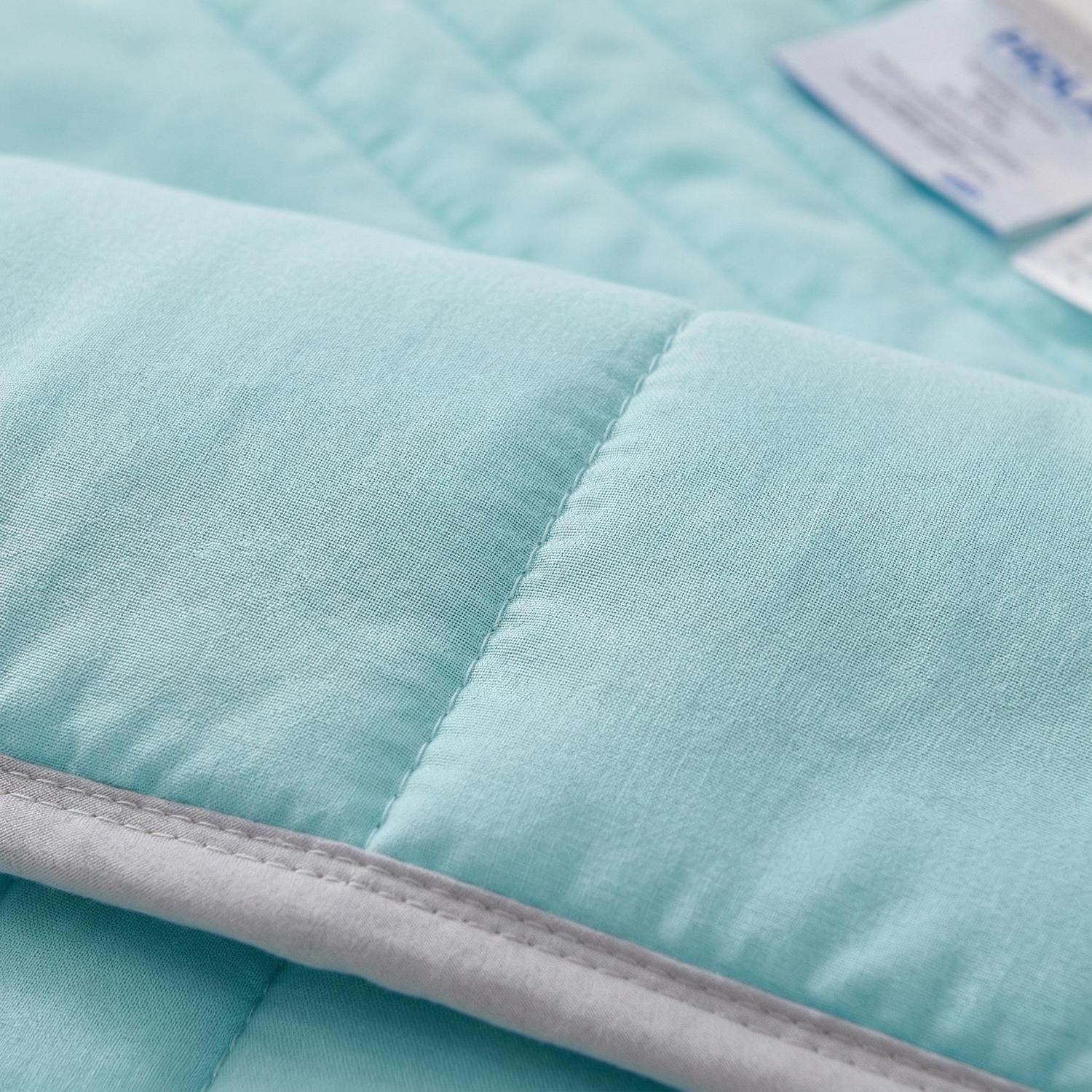Close-up of a light blue Cool Silk Summer Quilt with quilted stitching and a grey trim.