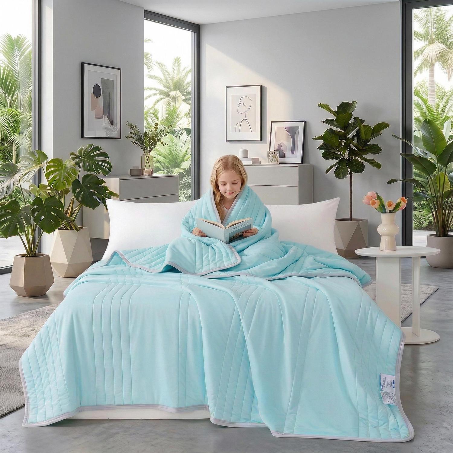 Young girl wrapped in a light blue, silk-like summer quilt with a quilted diamond pattern, reading in bed.