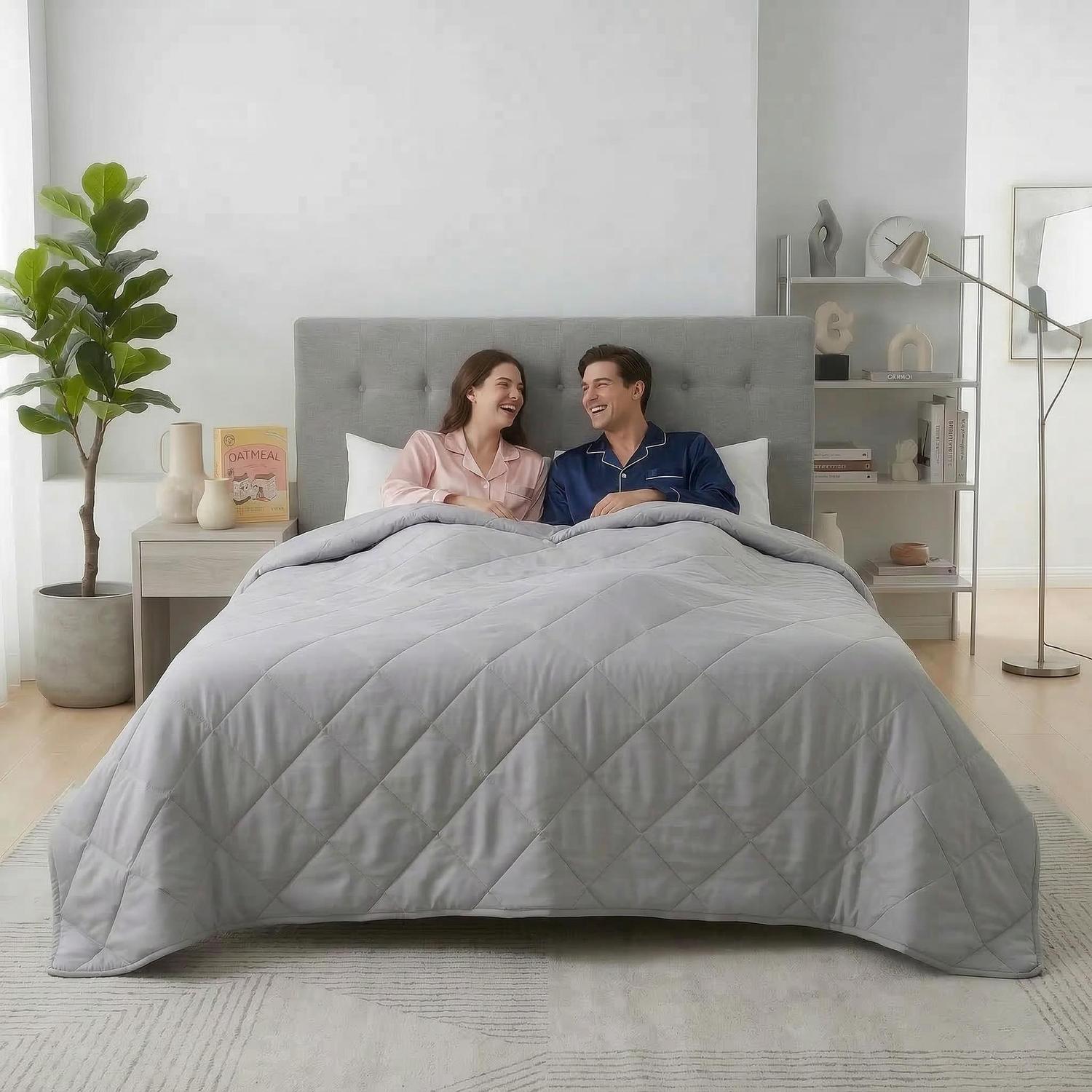 Light gray quilted cooling blanket on a bed with a couple smiling, ideal for warm weather.