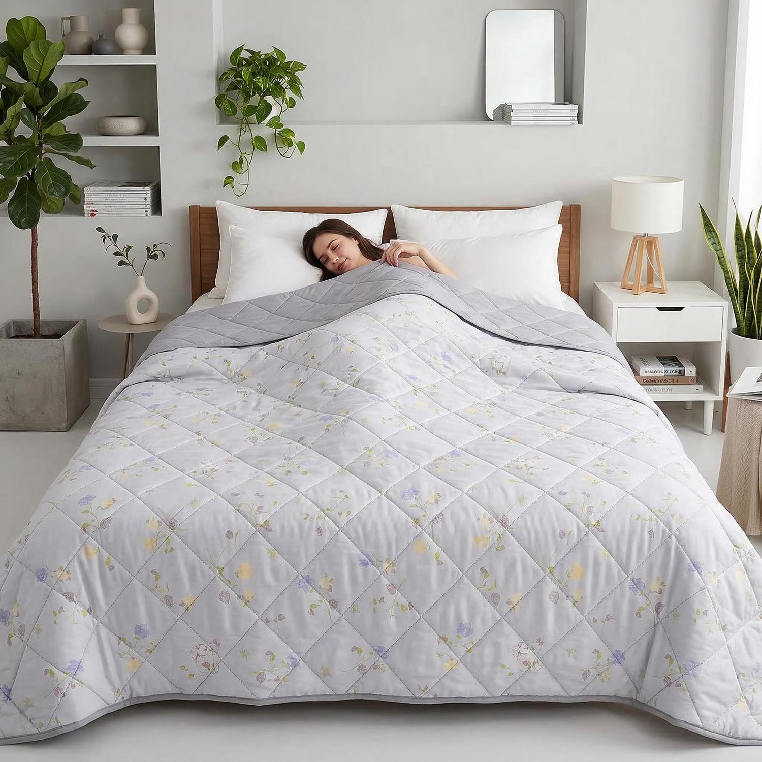 Woman sleeping under a light grey cooling blanket with subtle floral patterns and diamond quilting.