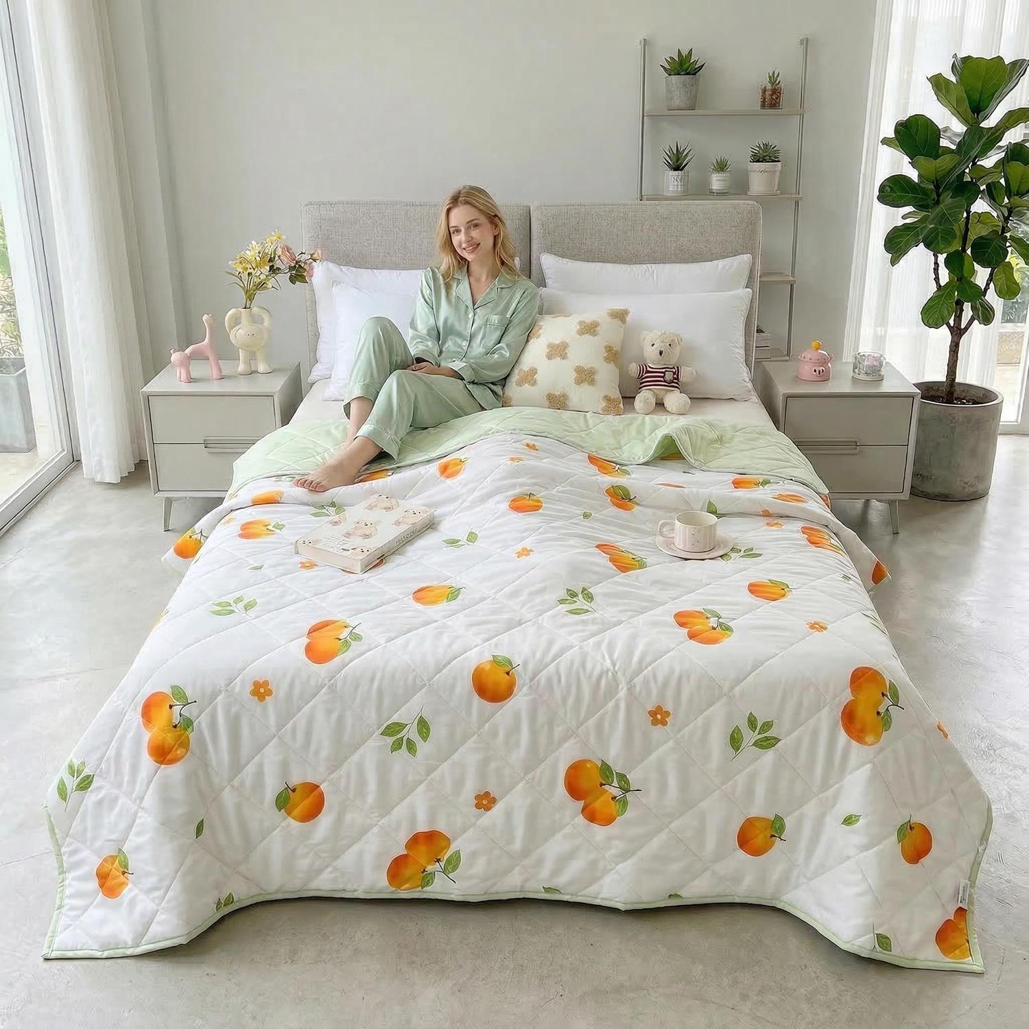 Woman on bed with white quilted cooling blanket featuring orange peach print and green trim.