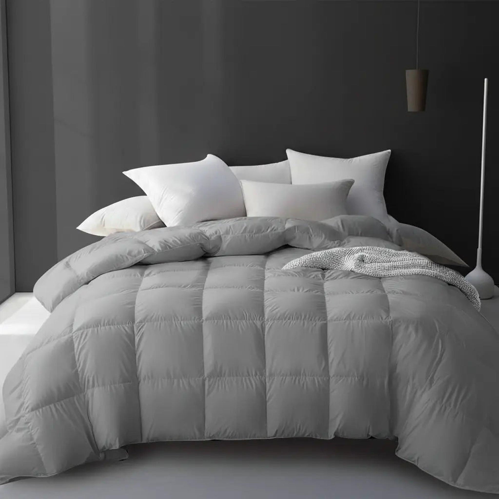 Soft gray cooling goose down comforter with a square quilted design on a bed with white pillows.