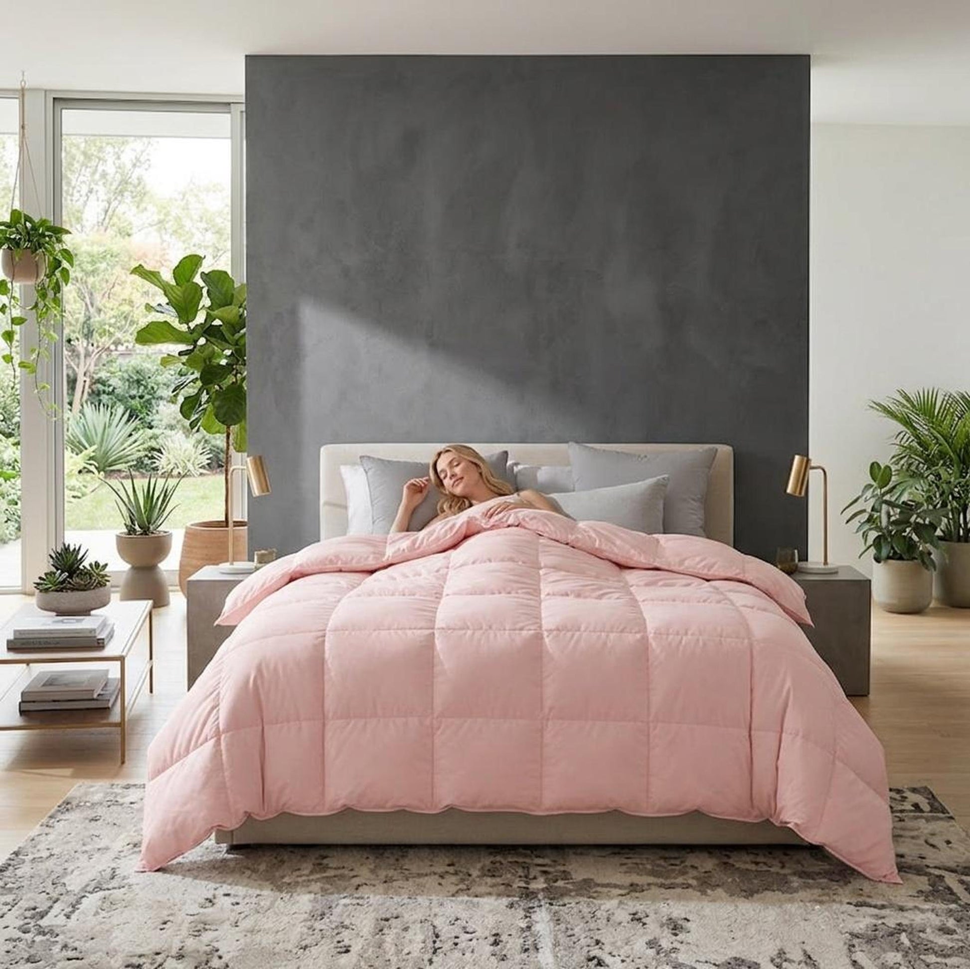 Woman sleeping peacefully under a soft pink goose down comforter in a modern bedroom.