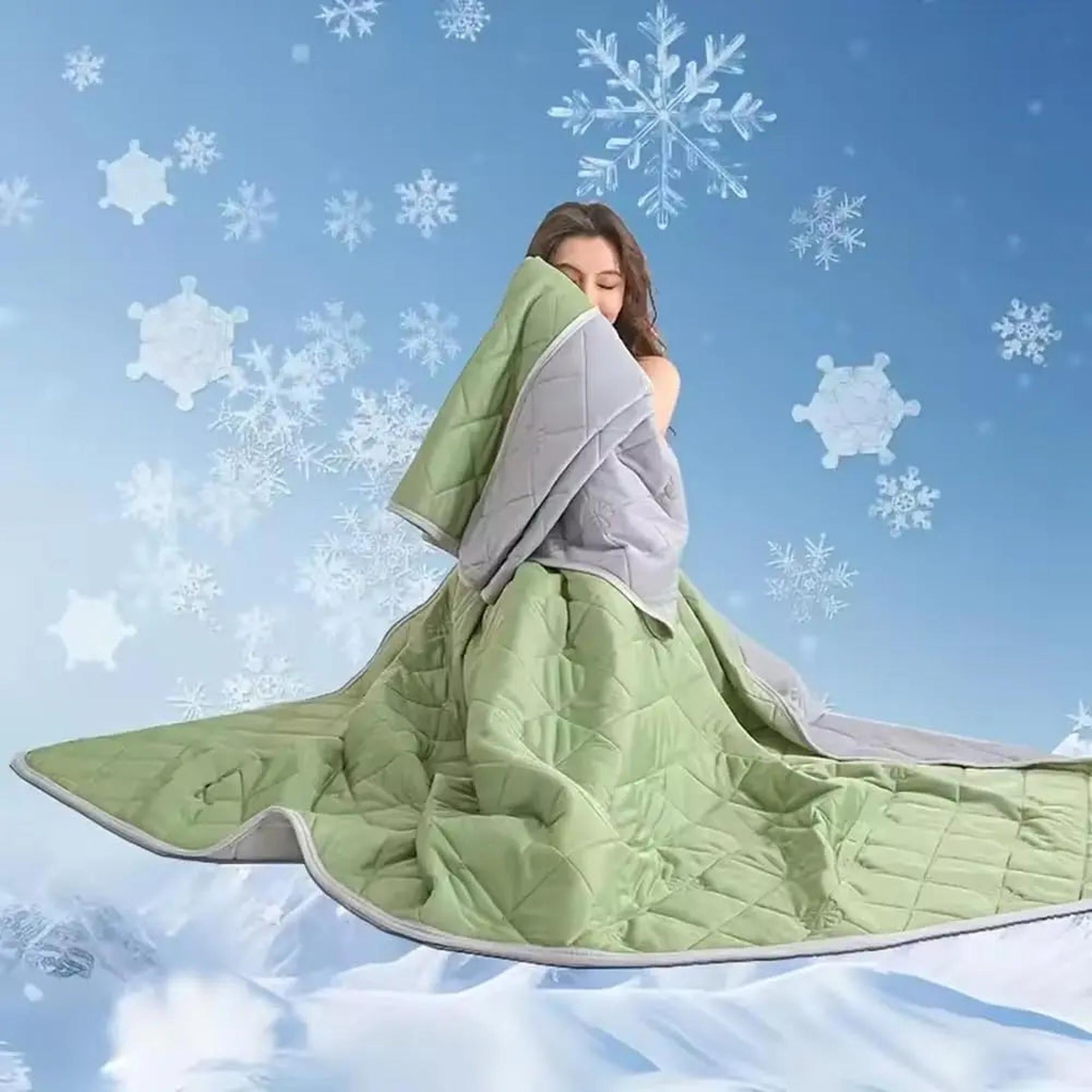 Woman wrapped in a reversible green and grey quilted cooling blanket with snowflakes in the background.