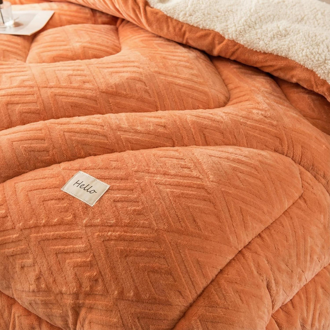 Orange and white coral fleece weighted blanket on a bed with a mother and child.